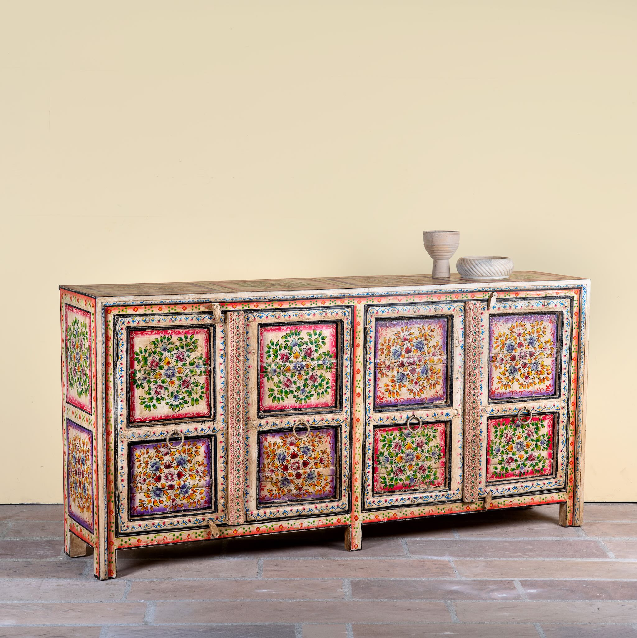 Side angle image of a boho style hand painted sideboard with reclaimed old Indian door decoration. Unique cabinet with floral design.