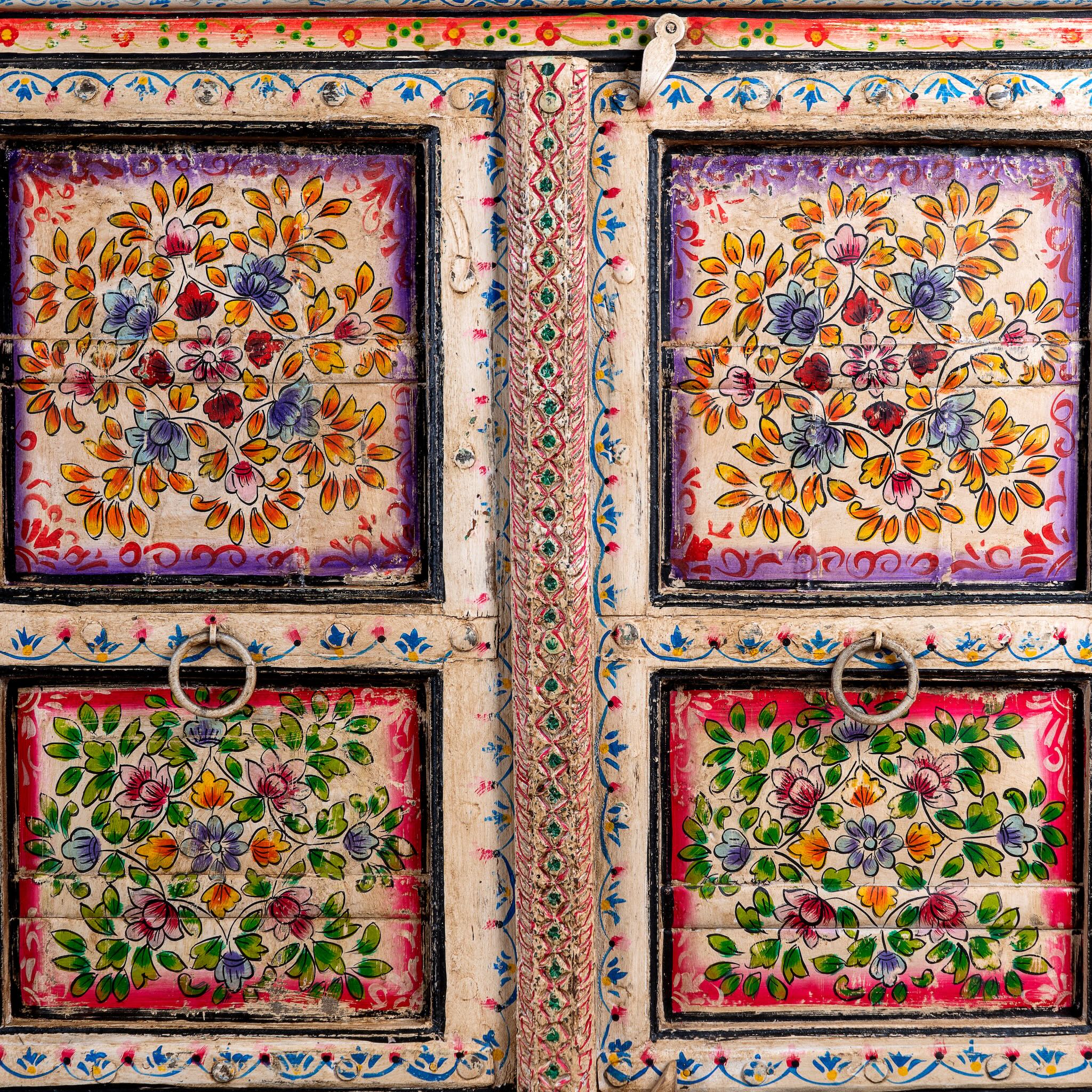 Close up image of a boho style hand painted sideboard with reclaimed old Indian door decoration. Unique cabinet with floral design.