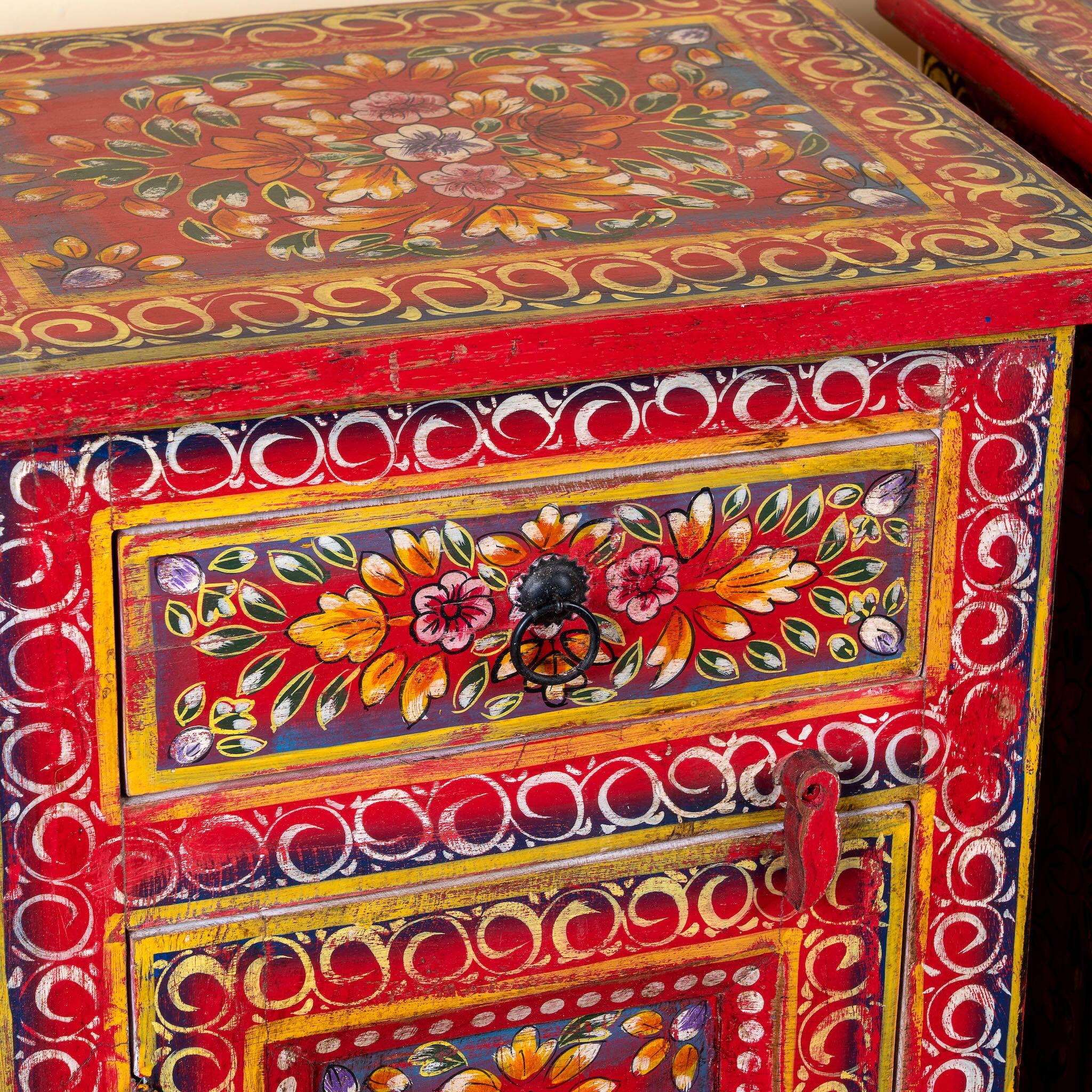 Close up image of a Joven pair of hand painted reclaimed wood nightstands with one drawer, one cabinet door, floral artwork, and vibrant red boho style finish.