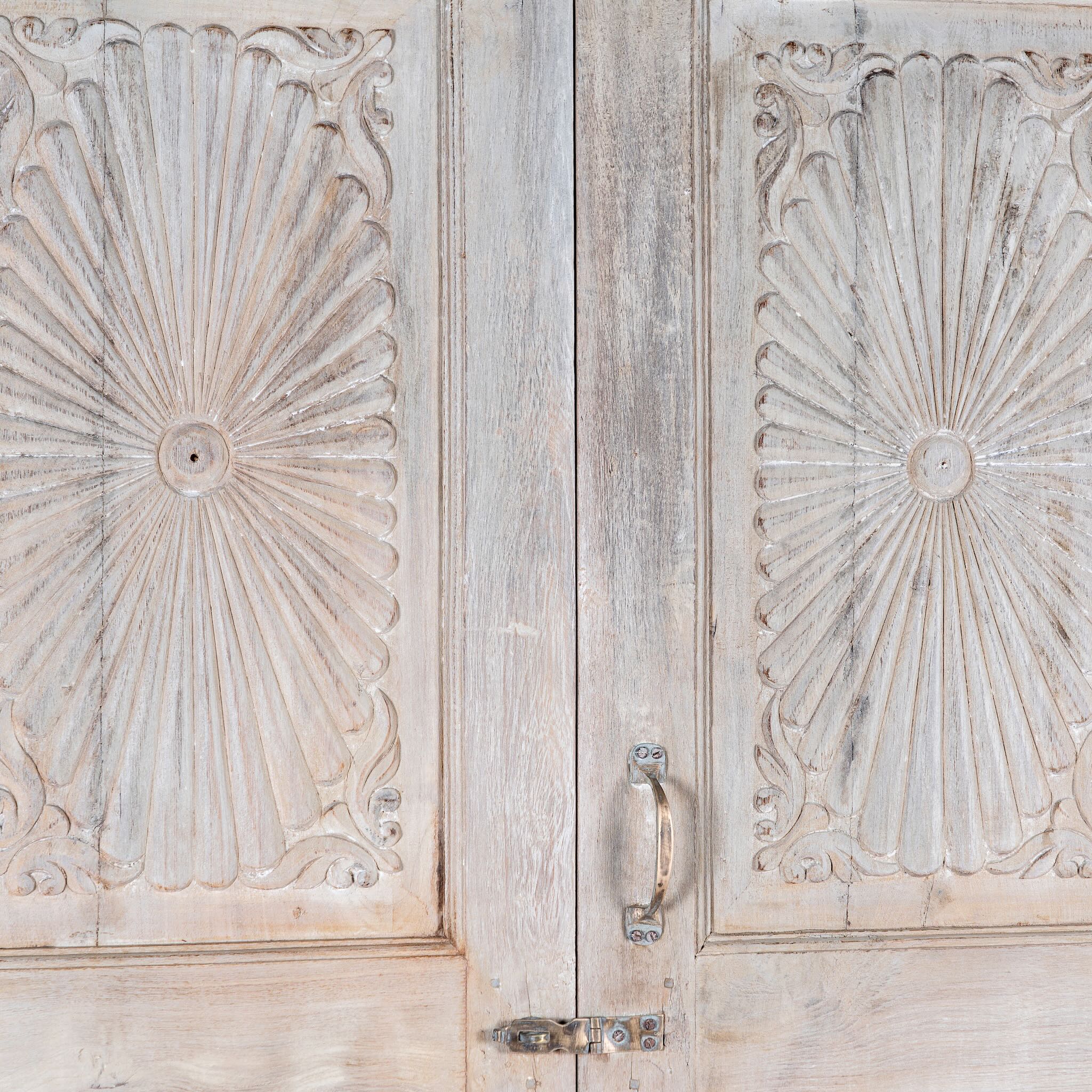 Close up image of a Kaiden reclaimed teak wood wardrobe with hand-carved Indian details, double doors, and vintage whitewashed finish.