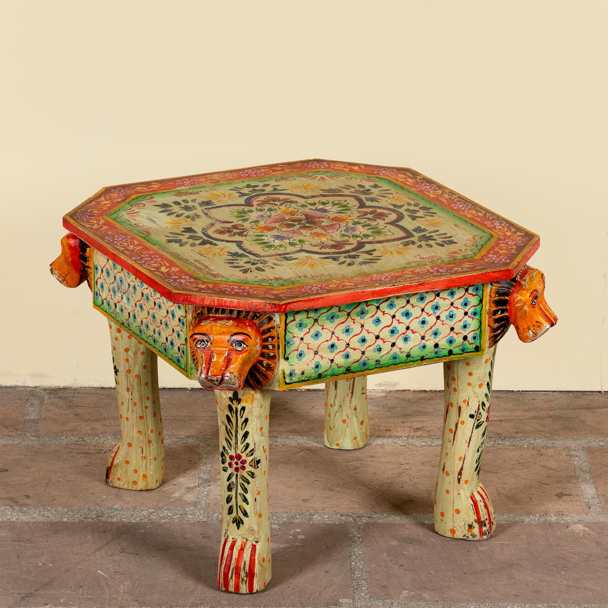 Side angle image of a Kaliana hand-painted reclaimed wood coffee table with sculpted tiger heads and colourful floral design 80cm