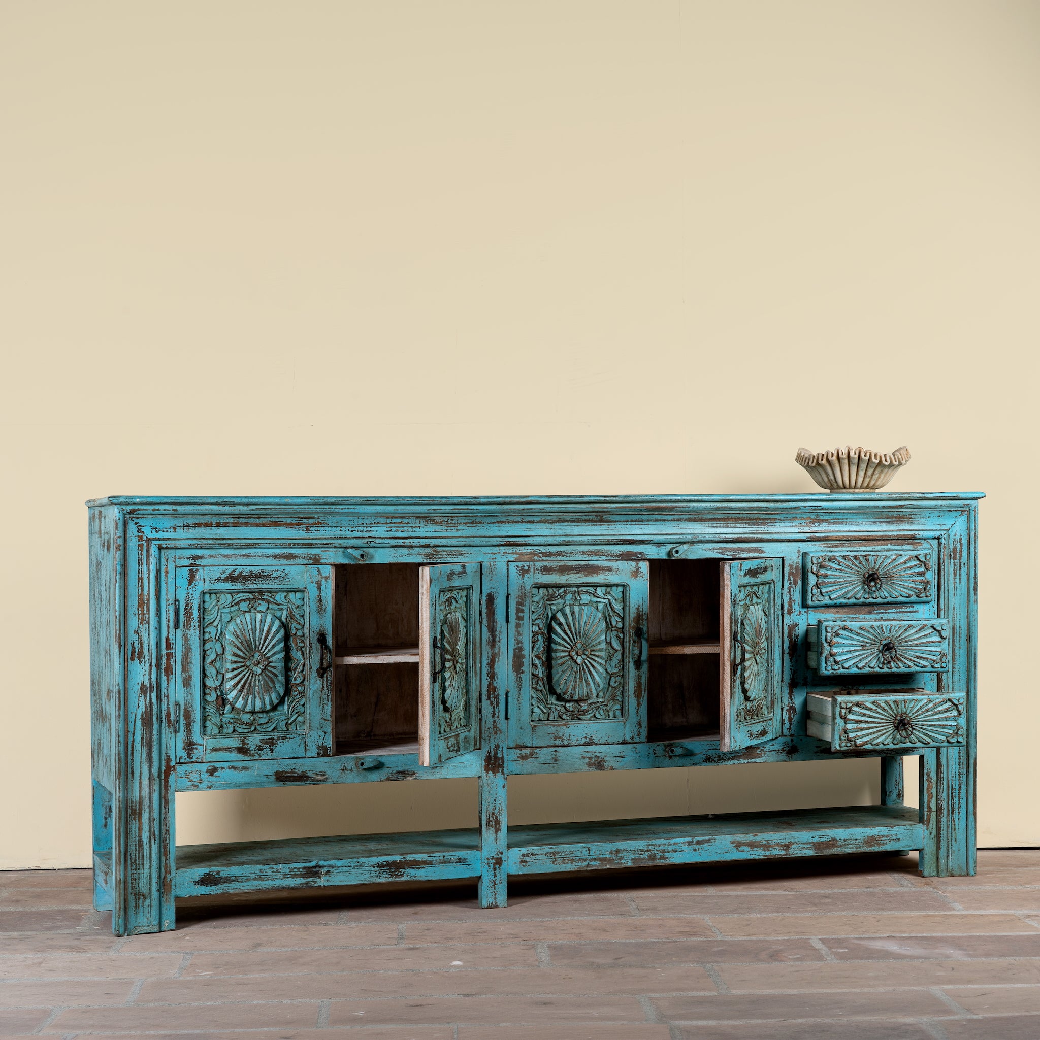 Side angle image showing open doors of a Kalpana reclaimed wood console table with blue distressed finish, carved doors, three drawers, enclosed storage and open lower shelf.