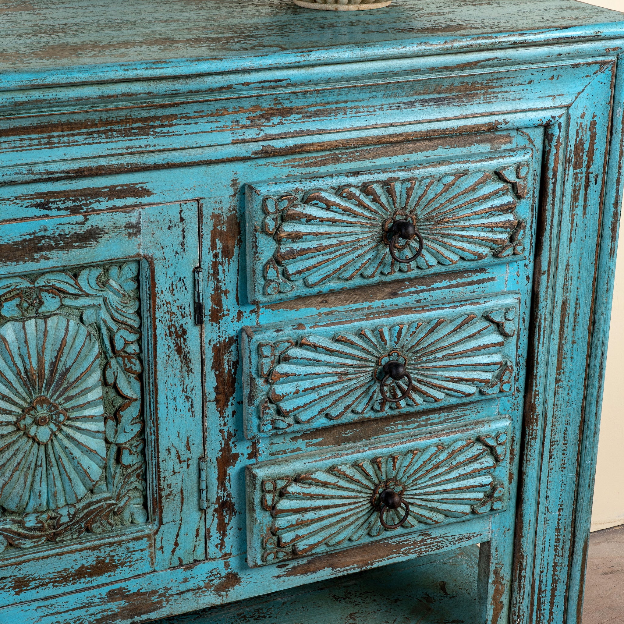 Close up image of a Kalpana reclaimed wood console table with blue distressed finish, carved doors, three drawers, enclosed storage and open lower shelf.