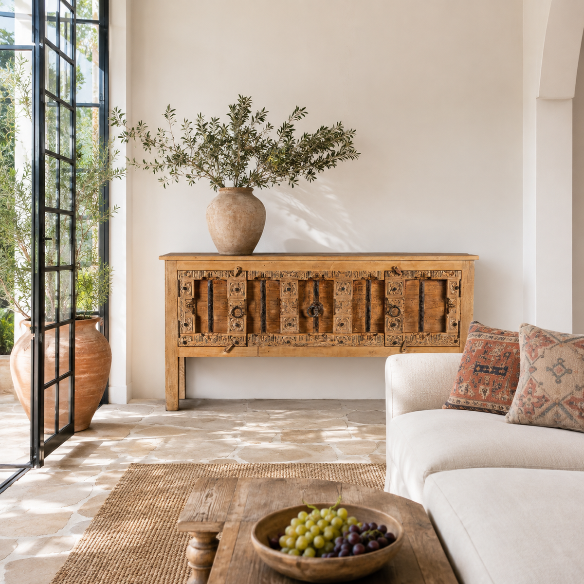 Lifestyle image of a Kanan console table made from old teak door panels, featuring traditional hand-carved details, iron ring accents, and built-in storage in a natural rustic finish.