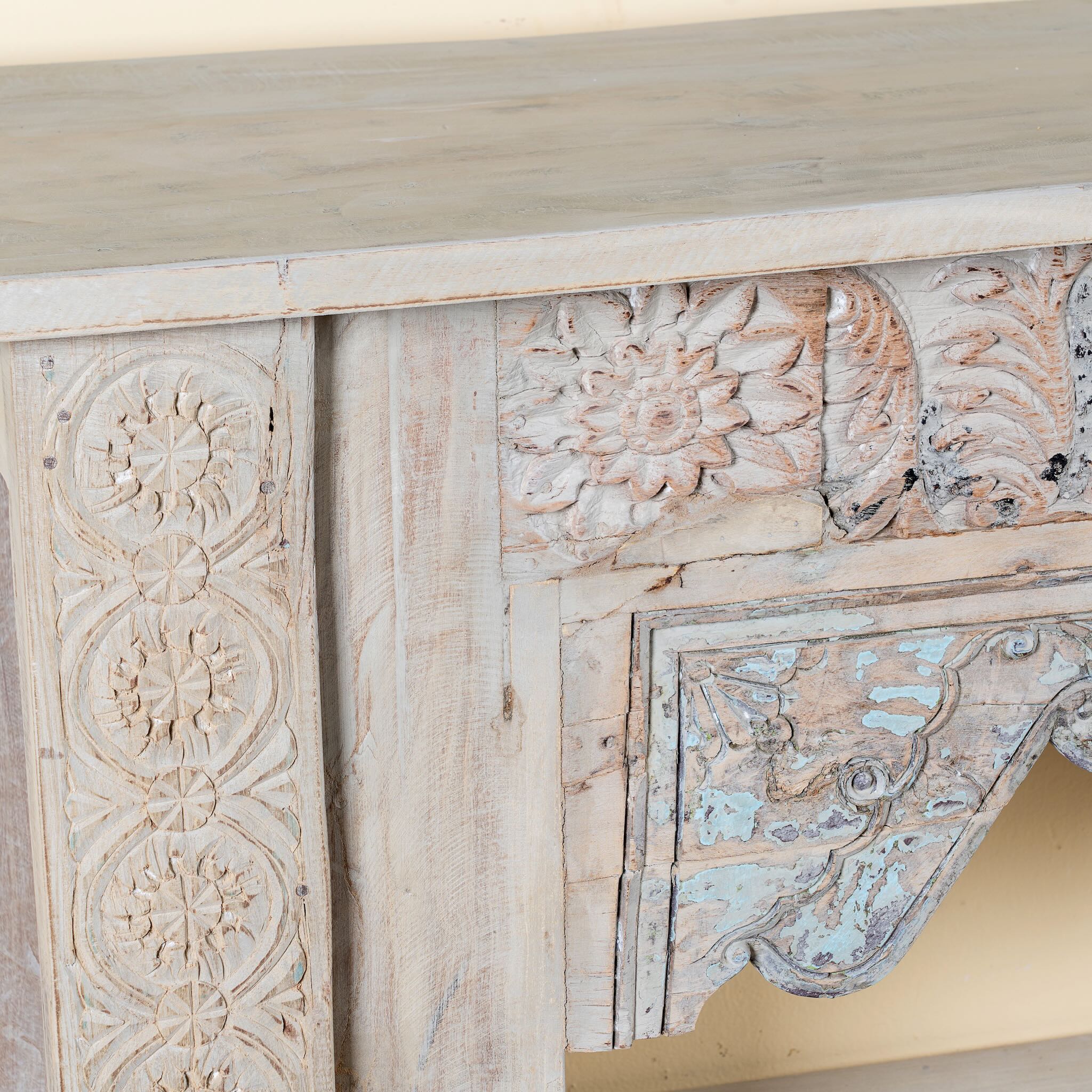 Close up image of a Karam reclaimed teak console table with hand-carved Indian details, lower shelf, and vintage whitewashed finish.