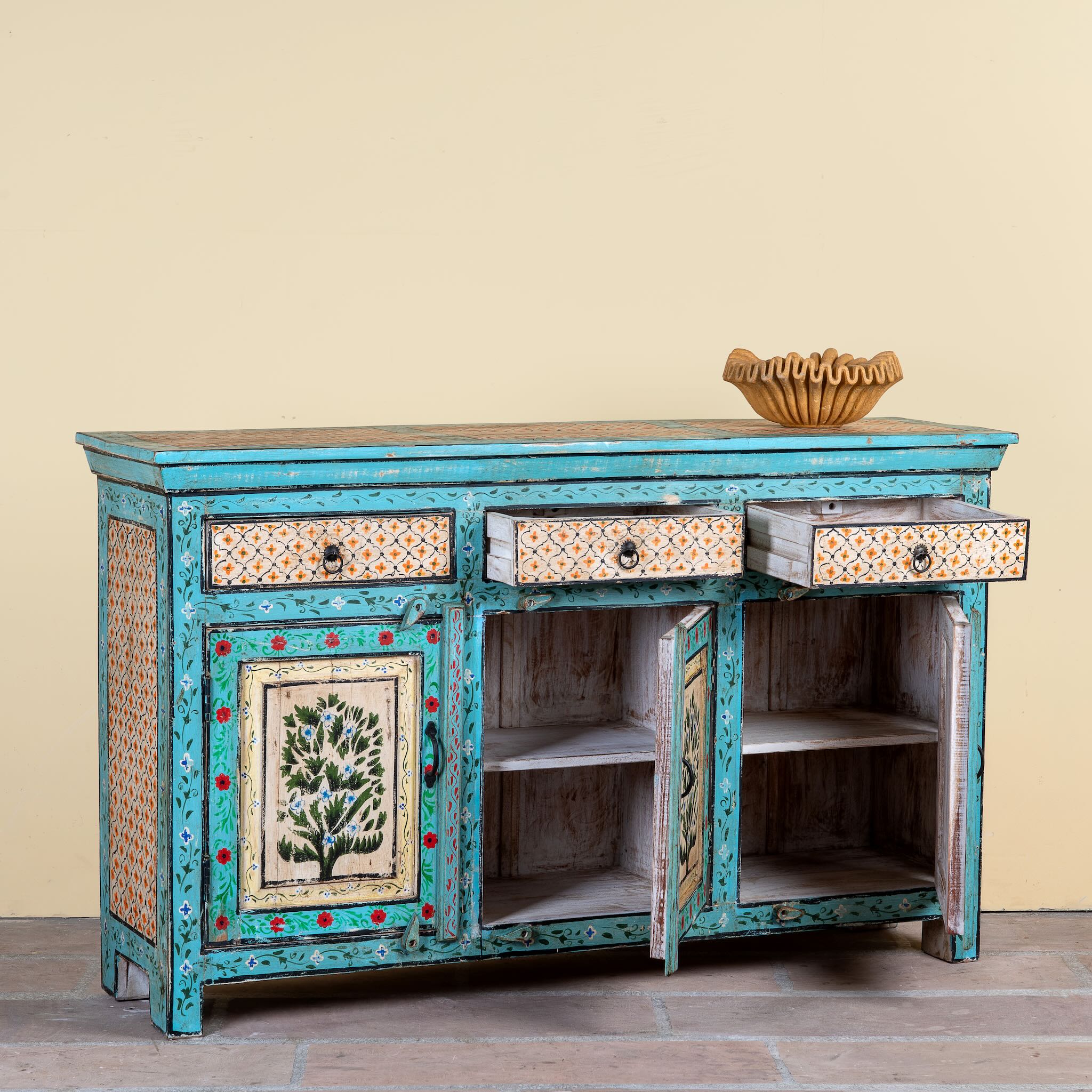 Side angle image with open door of a Kaveh hand painted reclaimed wood sideboard in boho style with three doors, three drawers, floral details, and distressed turquoise finish.