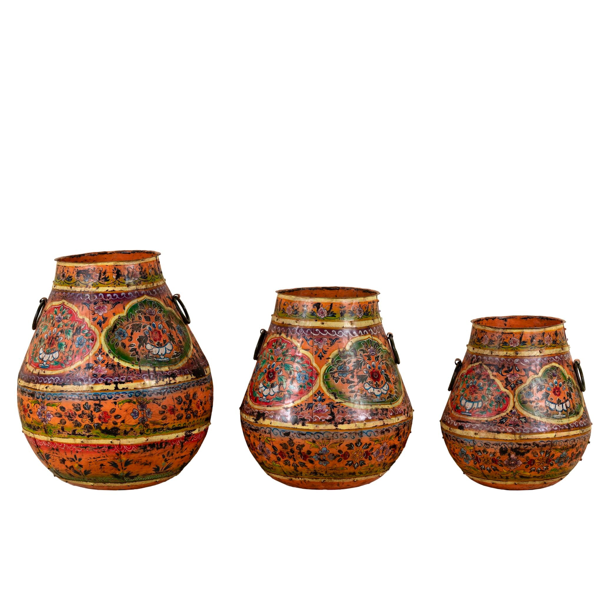 White background image of a set of 3 hand-painted decorative iron pots in orange tones with traditional Indian floral and paisley motifs – ideal for vintage home accessories and painted iron decoration.