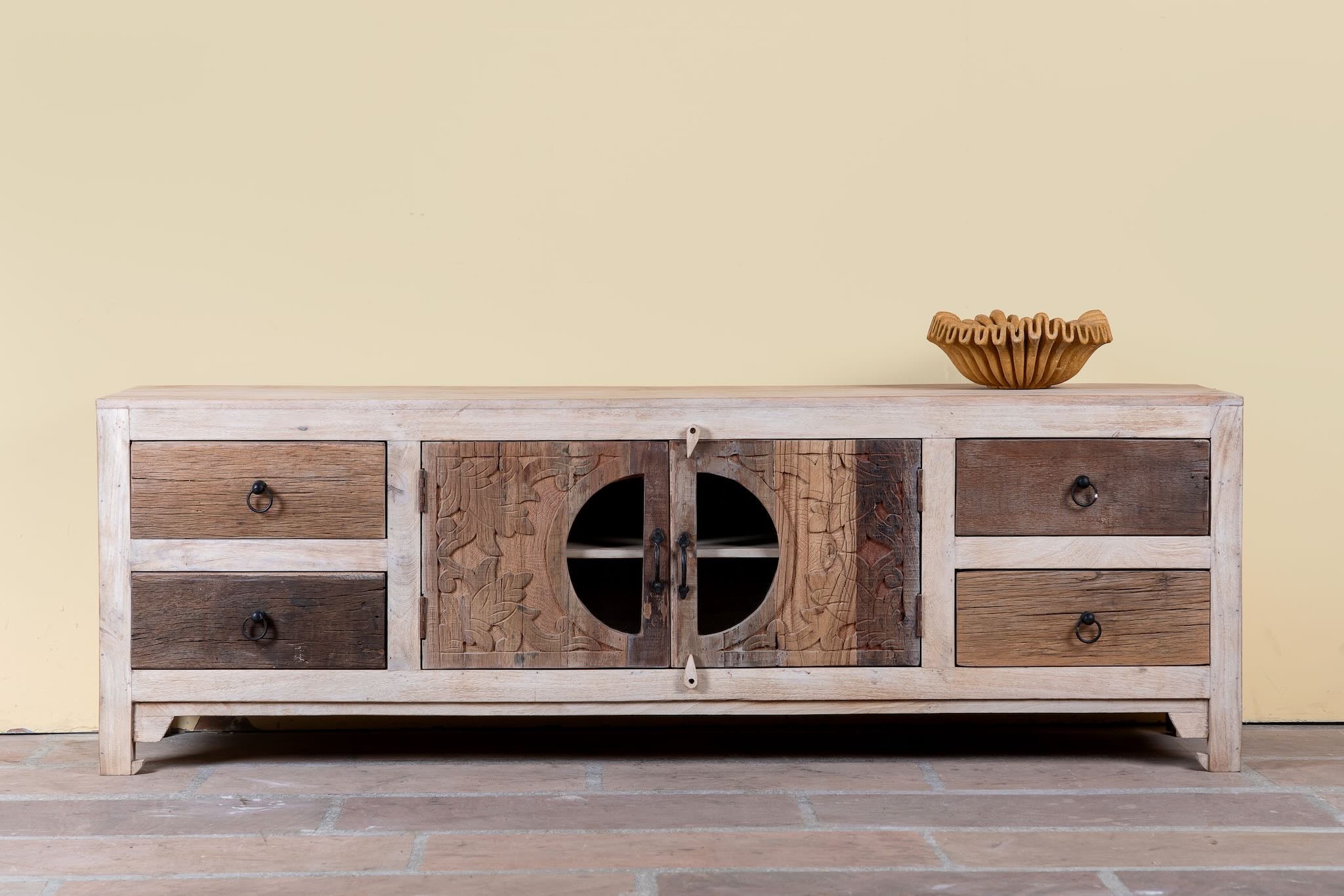 Kishen handcrafted reclaimed wood lowboard with driftwood front detailing, carved cabinet doors, four drawers, and natural rustic boho style finish.