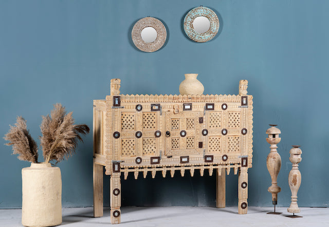Side angle image of an antique Indian treasure chest in solid teak with hand-carved detailing and sandblasted finish. A vintage home accessory ideal for Indian decor, 122 × 96 × 40 cm.