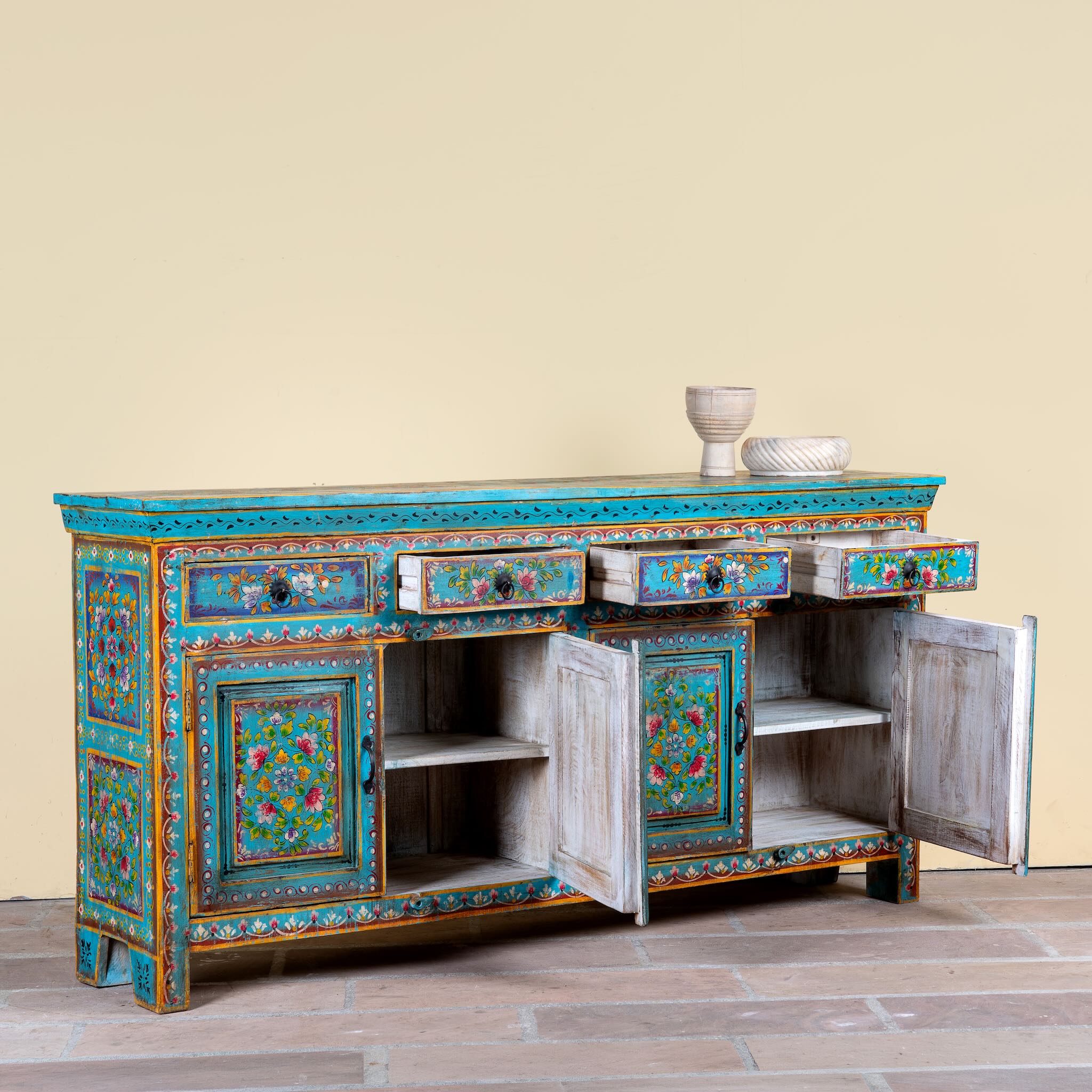 Side angle image with open doors of a Laksh hand painted reclaimed wood sideboard in boho style with distressed vintage finish and traditional Indian floral artwork.