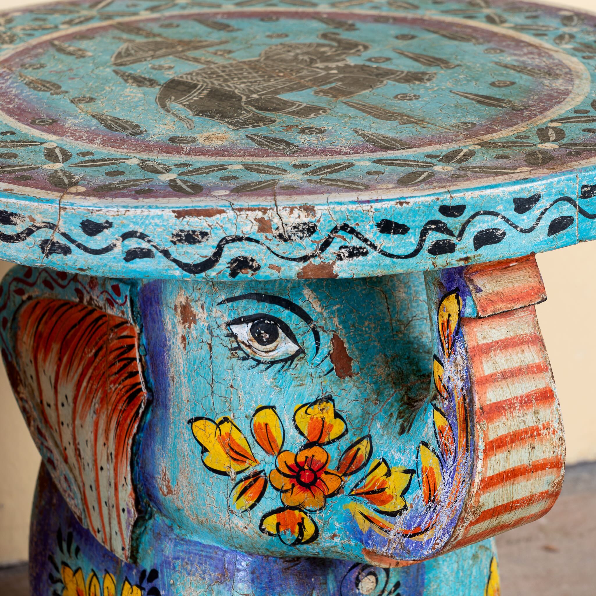 Close up image of a blue Leo hand painted solid wood elephant side table with traditional Indian artwork, available in yellow, red, and turquoise boho style designs.