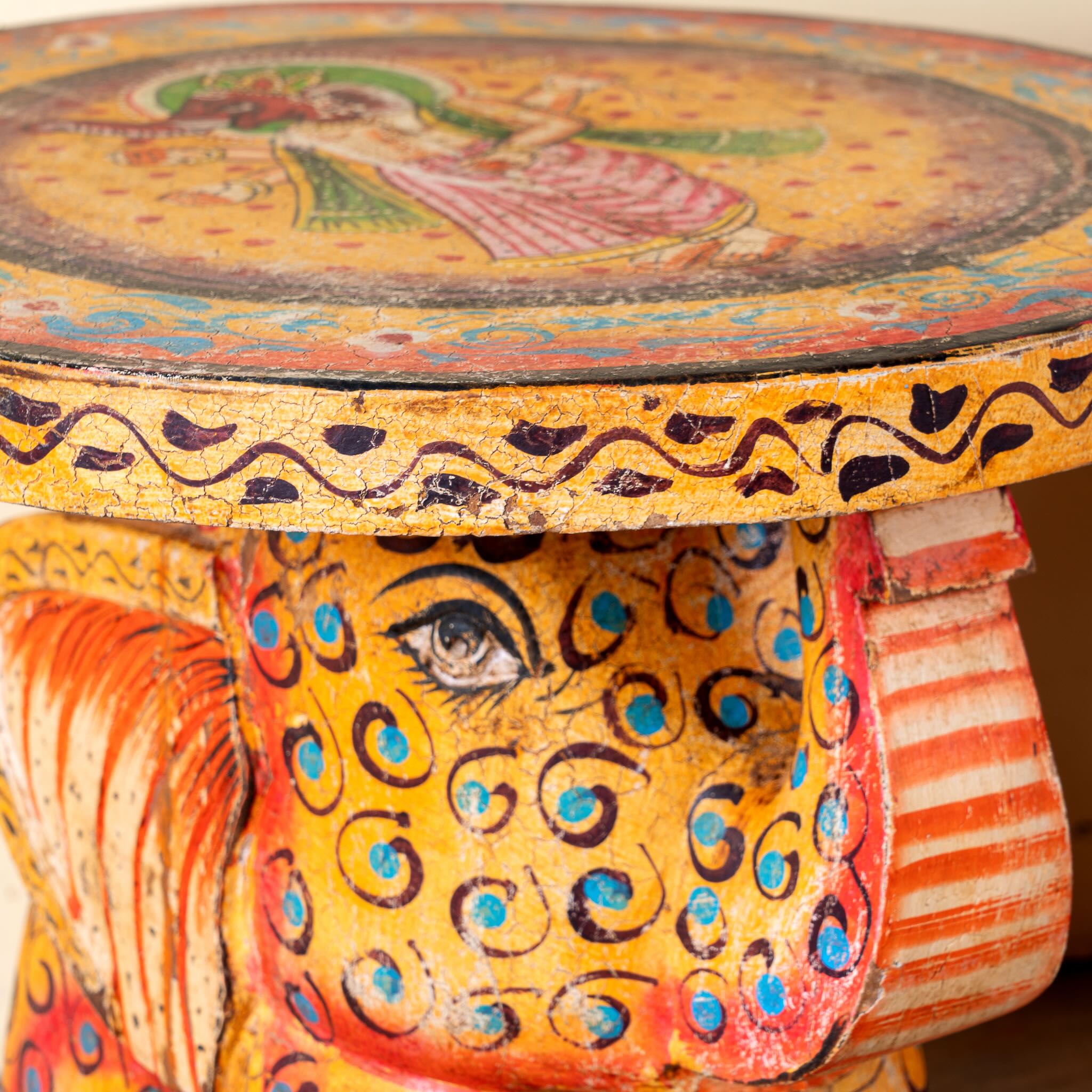 Close up image of a yellow Leo hand painted solid wood elephant side table with traditional Indian artwork, available in yellow, red, and turquoise boho style designs.