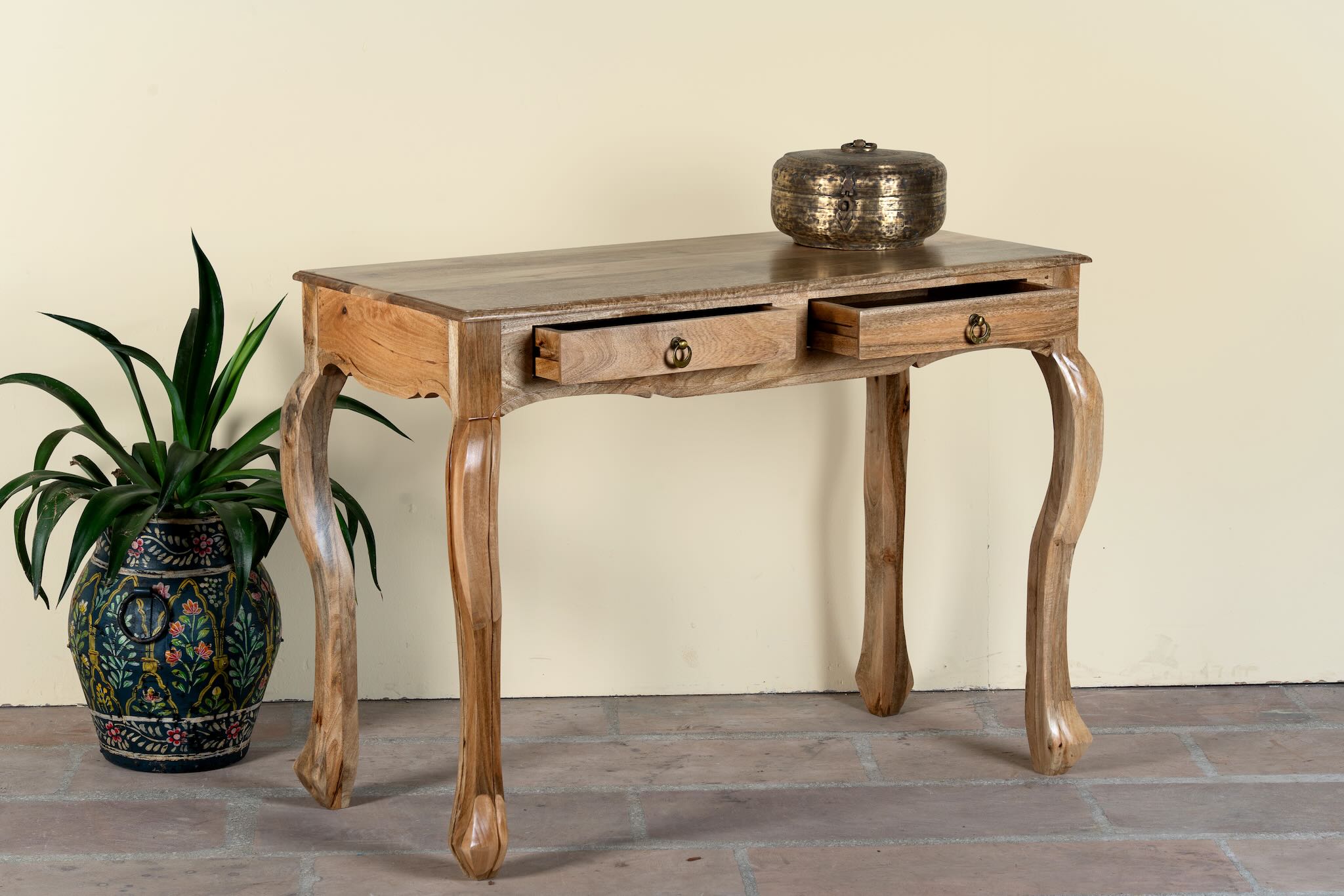 Side angle image with open drawers of a desk made of natural mango wood with 2 drawers and carved legs.