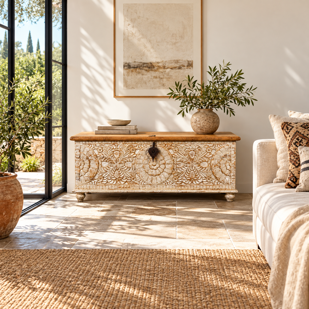 Lifestyle image of a hand-carved mango wood chest box with floral motifs, whitewashed finish, and iron handles – vintage home accessory for rustic and elegant interiors.