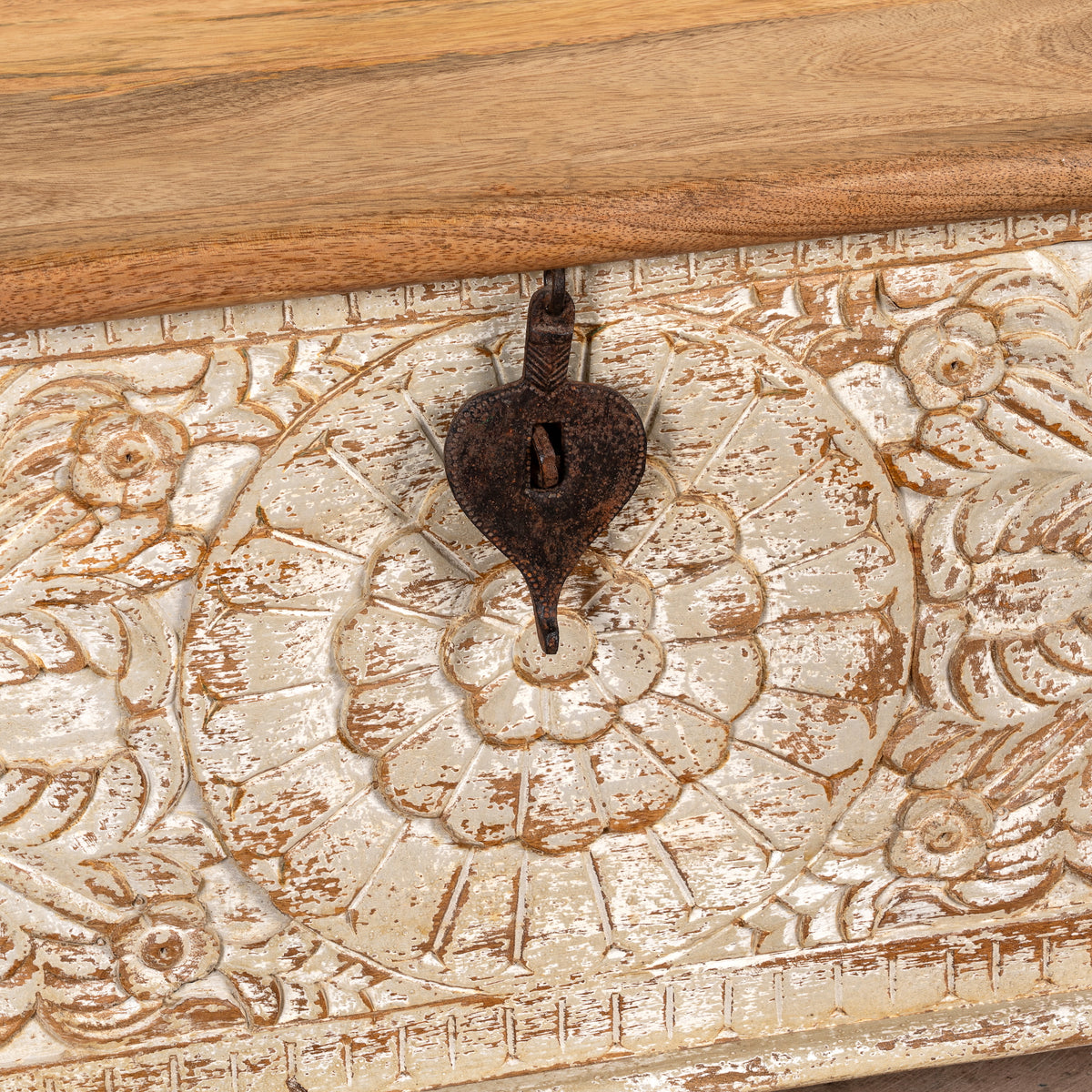 Close up image of a hand-carved mango wood chest box with floral motifs, whitewashed finish, and iron handles – vintage home accessory for rustic and elegant interiors.