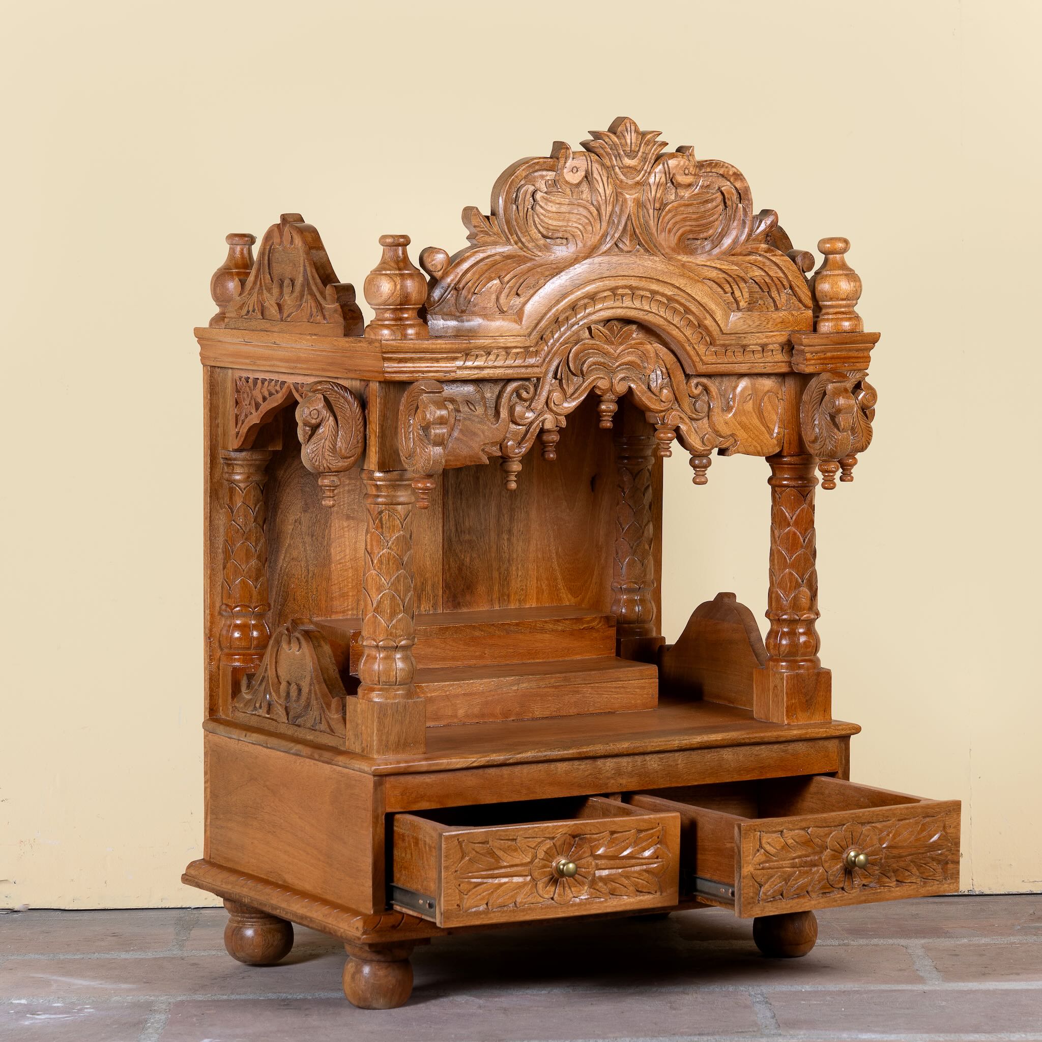 Side angle image with open drawers of a Meher hand carved mango wood mandir with traditional Indian temple details and two small drawers.