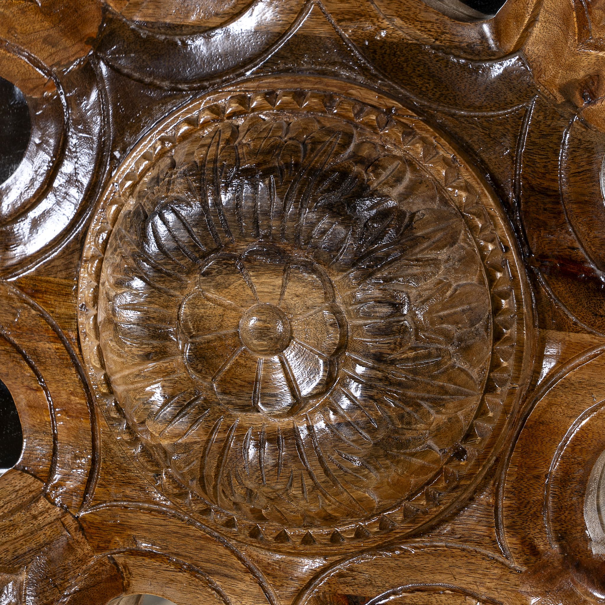 Close up image of a round mango wood mirror Ojis with hand-carved floral frame. A unique wall decor piece combining traditional Indian craftsmanship and organic design.
