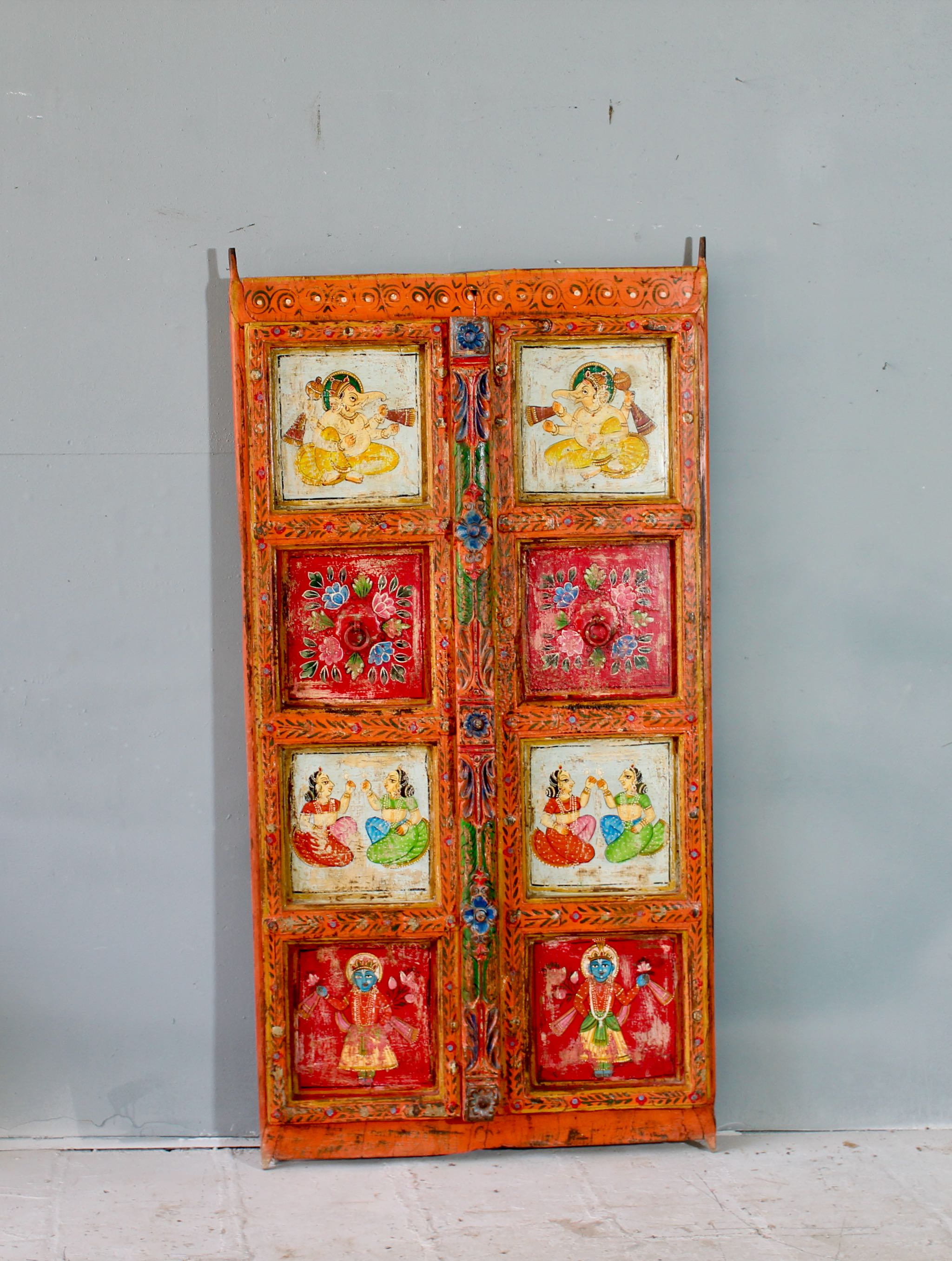 Hand-painted Indian antique teak wood door with mythological and folk motifs, vibrant orange frame, vintage wall panels for spiritual and artistic home decor.