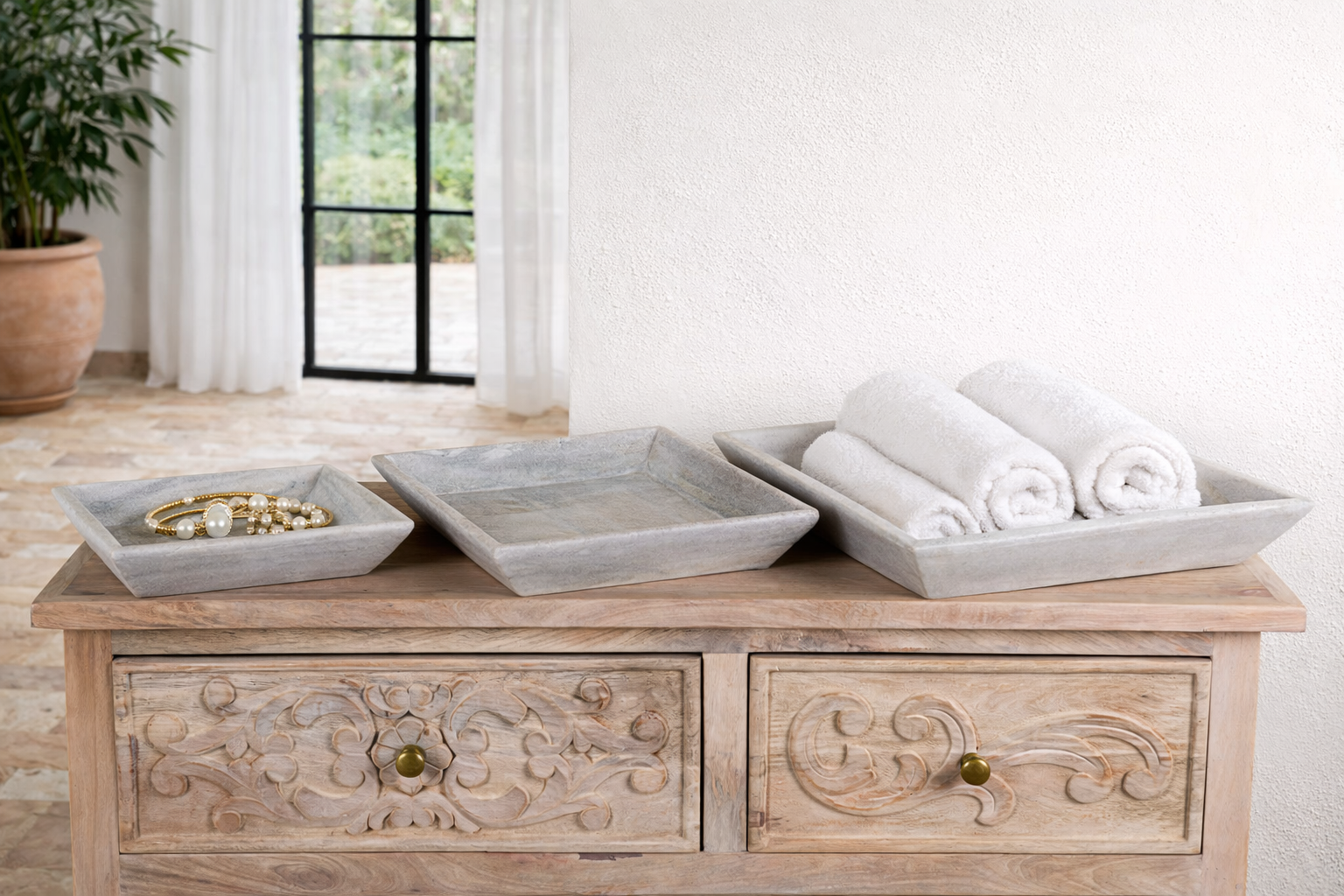 Lifestyle image of a set of 3 square white marble plates Nakul in varying sizes with sloped edges. A vintage home accessory and unique Indian decoration ideal for fruit, towels, or toiletries in vintage home decor settings.