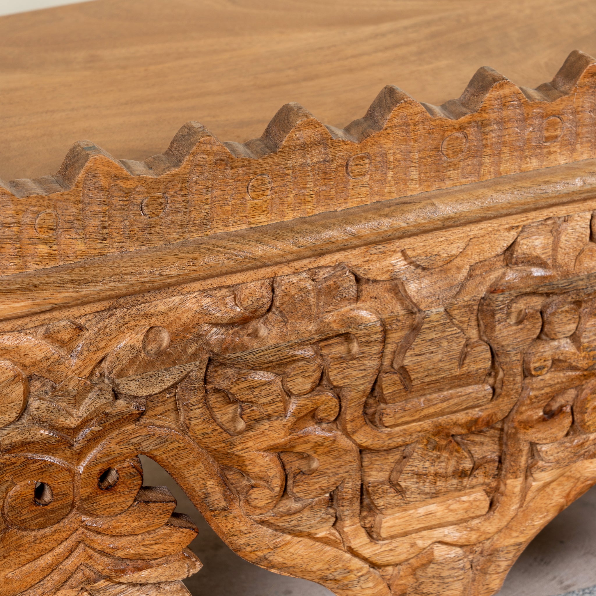 Close up image of a Nirvay hand carved mango wood wall shelf with floral carvings and decorative hanging leaf ornaments 90cm