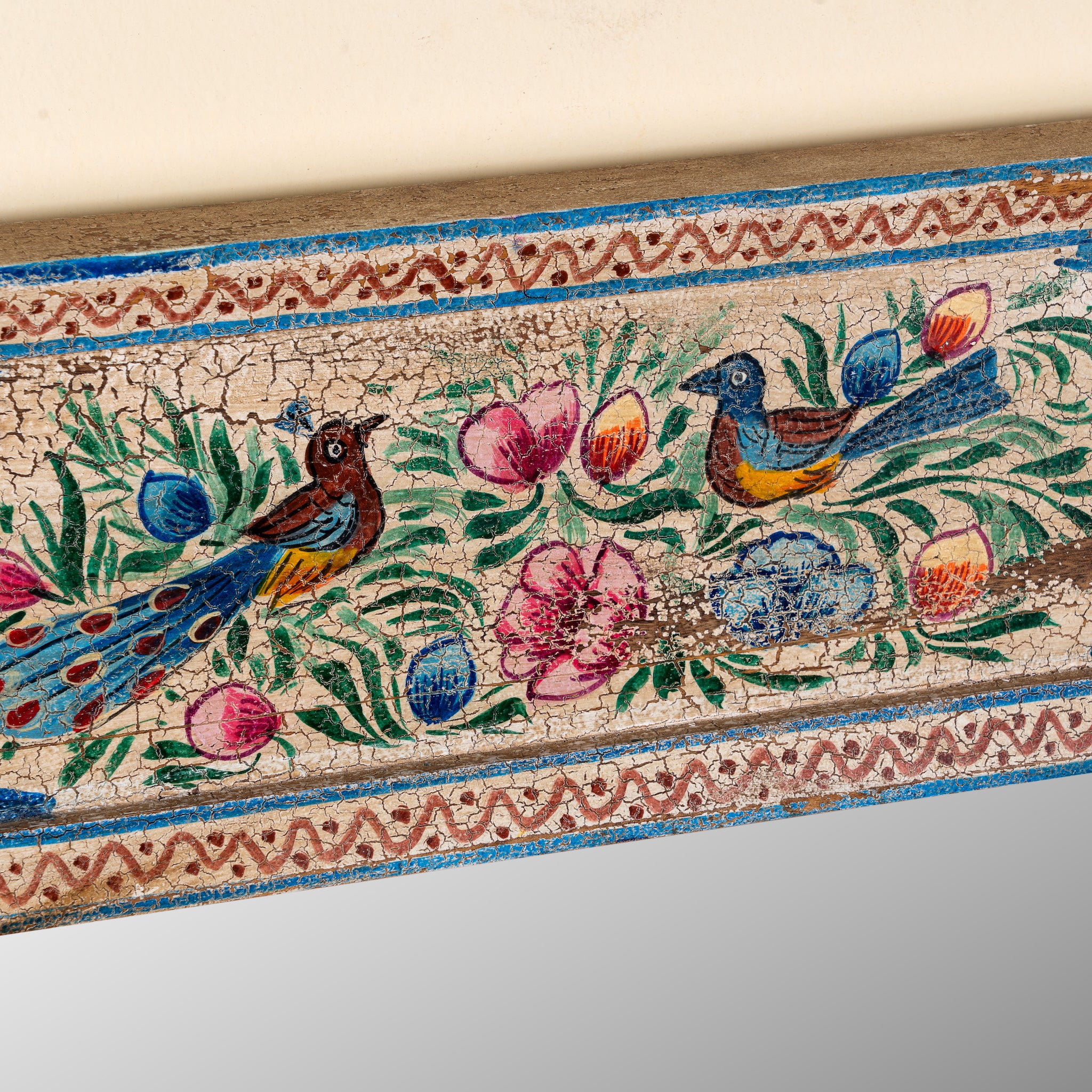 Close up image of a Nithya hand-painted reclaimed wood wall mirror featuring colourful peacocks, birds and floral Indian artwork, 90x90x5cm.