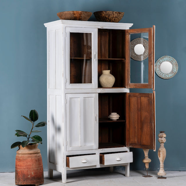 Side angle image with open doors of a shabby chic teak wood cabinet with glass doors, drawers, and compartments – sustainable living room furniture crafted from refurbished teak wood with a soft white finish.