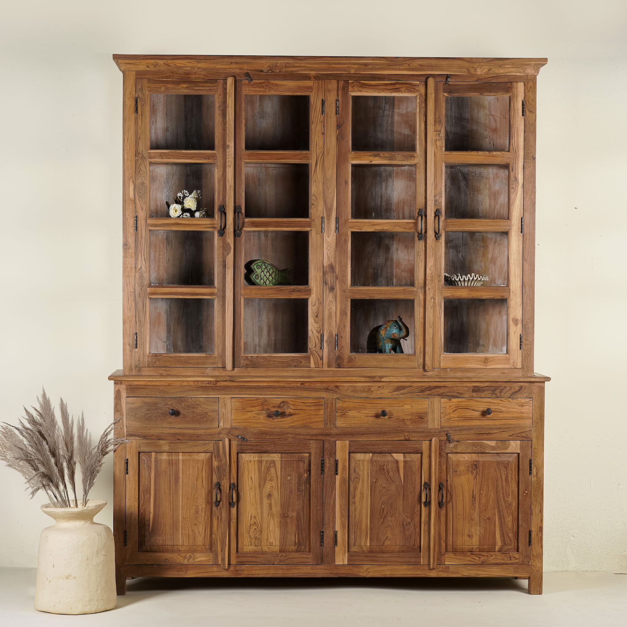 A large, solid teak wood showcase cabinet with glass panelled doors on the upper section and solid wood doors on the lower section, set against a neutral background.