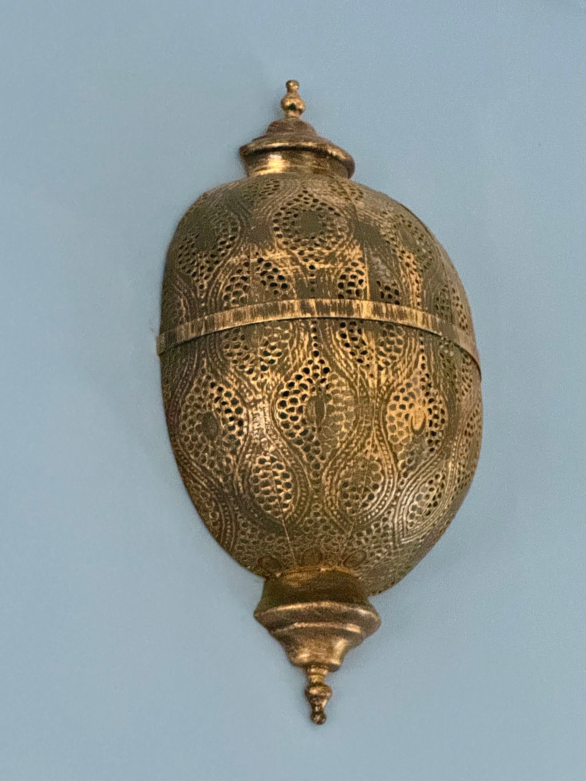 Antique-style hand-stamped iron wall lamp with brass finish, featuring intricate perforated detailing and vintage ornamental shape.