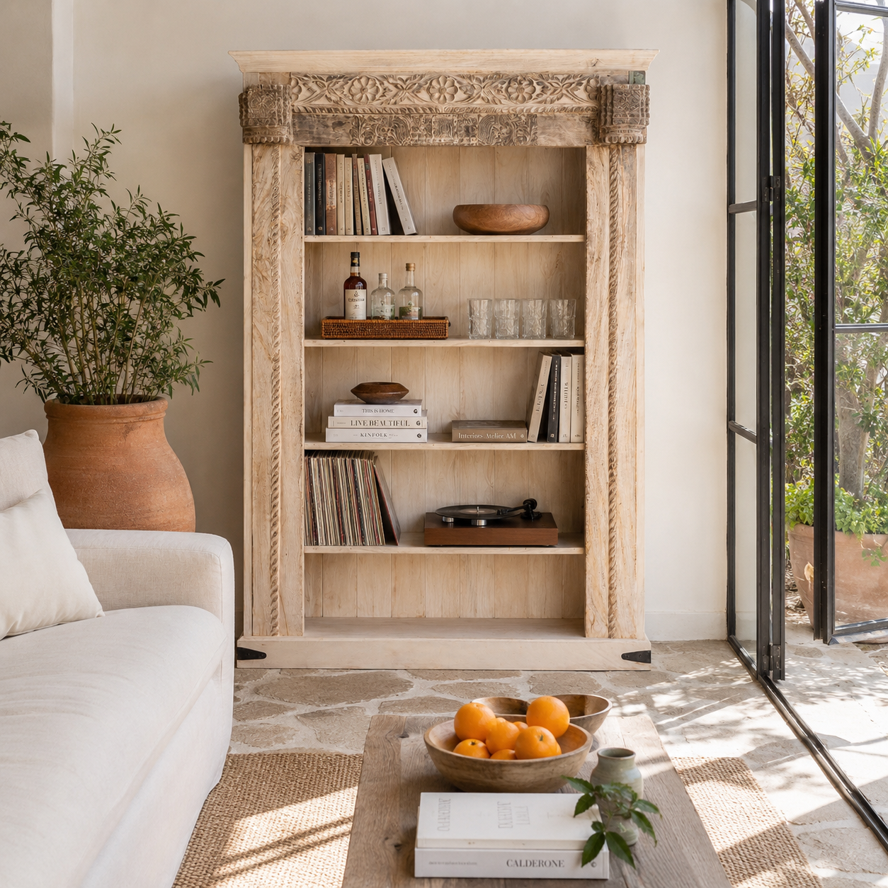 Lifestyle image of a hand-carved shelf made from reclaimed teak wood and mango wood, unique furniture with Ibiza-inspired finish, 150 × 208 × 52 cm.