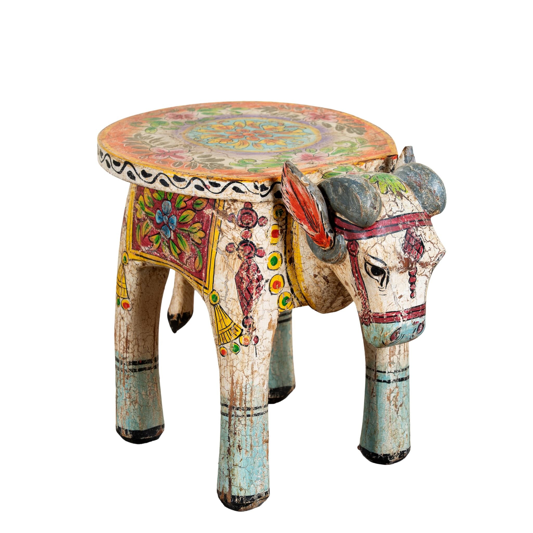 Side angle image of a hand-painted wooden Ram side table in the shape of a ram with curved horns, featuring colourful Indian folk art patterns, ideal for vintage and India-inspired home accessories.