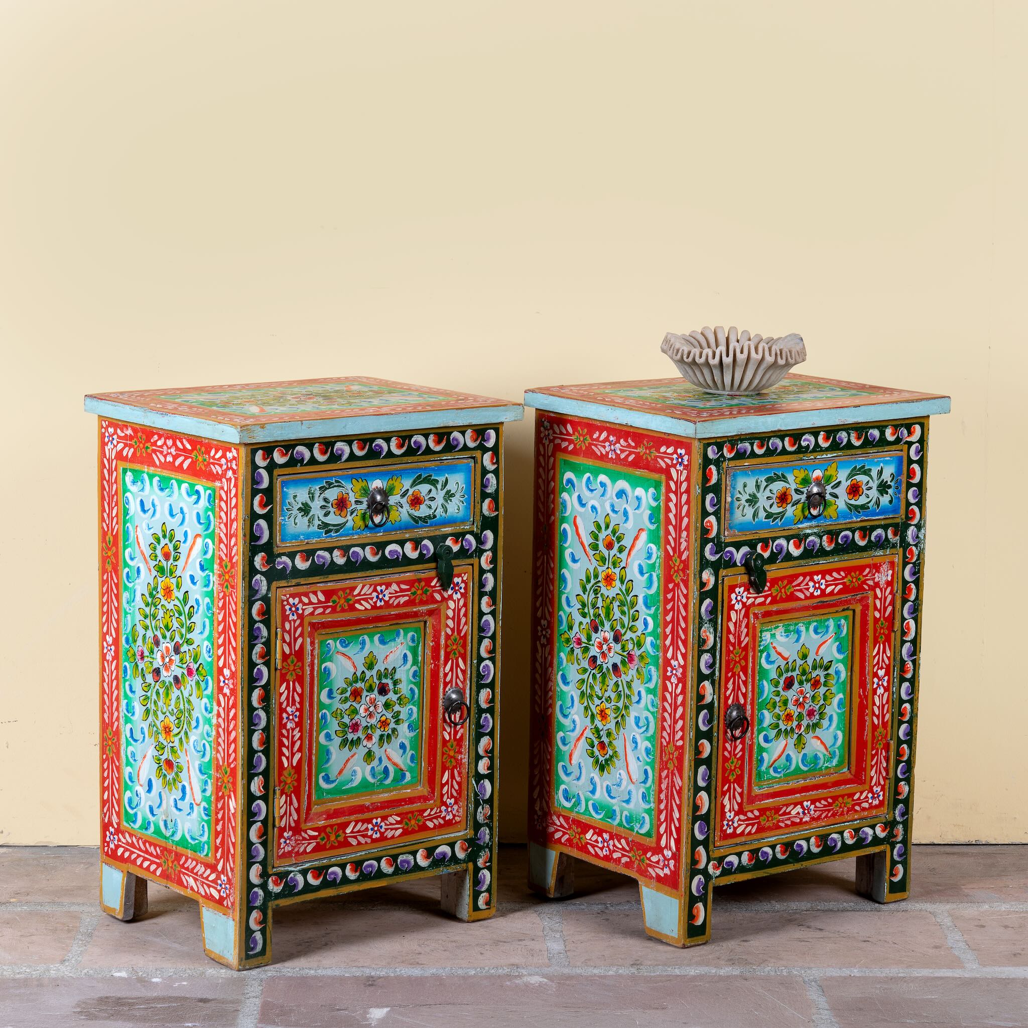 Side angle image of a hand-painted bedside table made from recycled wood – vintage night stands with carved mango wood furniture detailing and floral artistry.