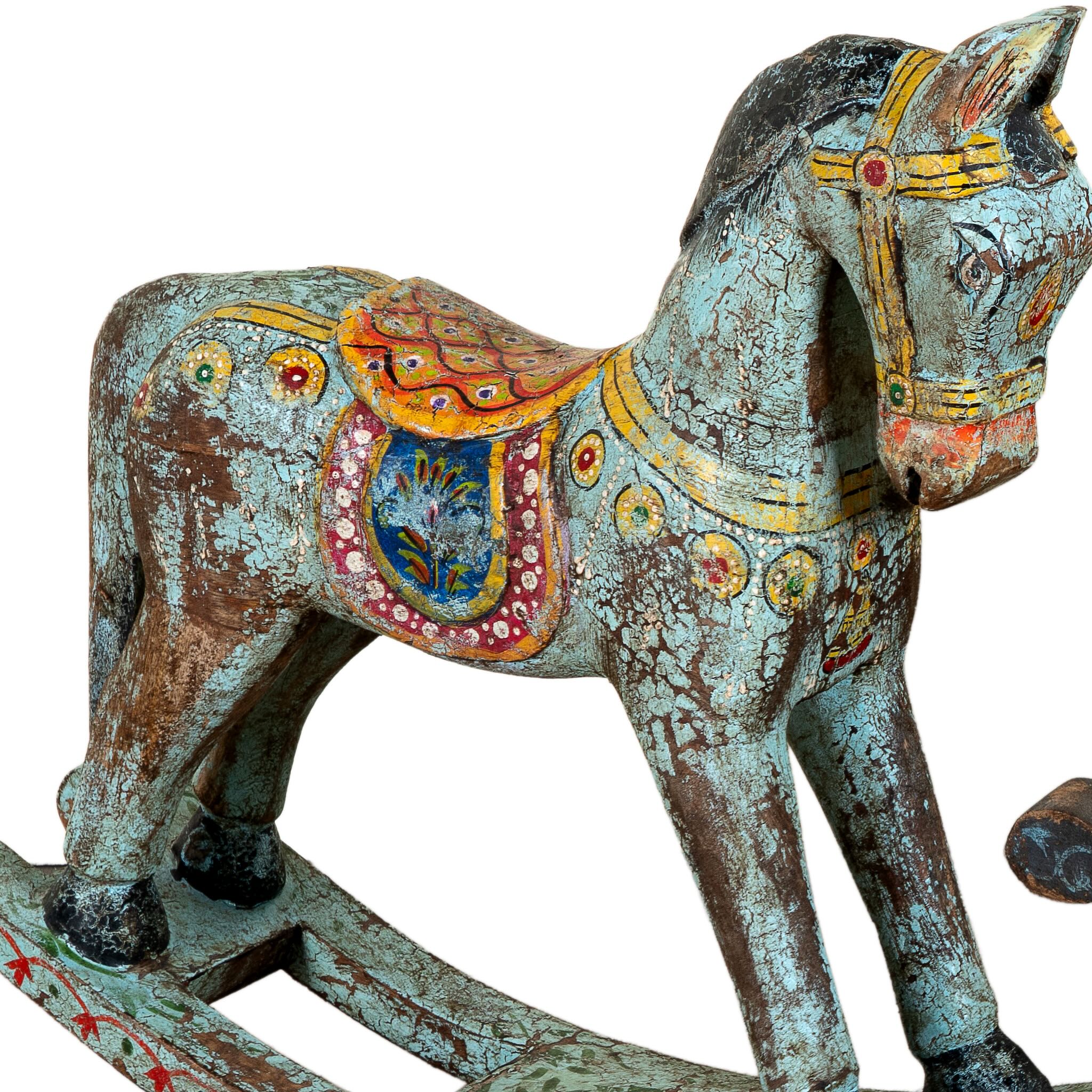 Close up image of a colorful hand-painted wooden rocking horses with ornate saddle patterns, crafted in India. Unique bohemian interior décor accents made from solid wood, perfect for shelves or sideboards.