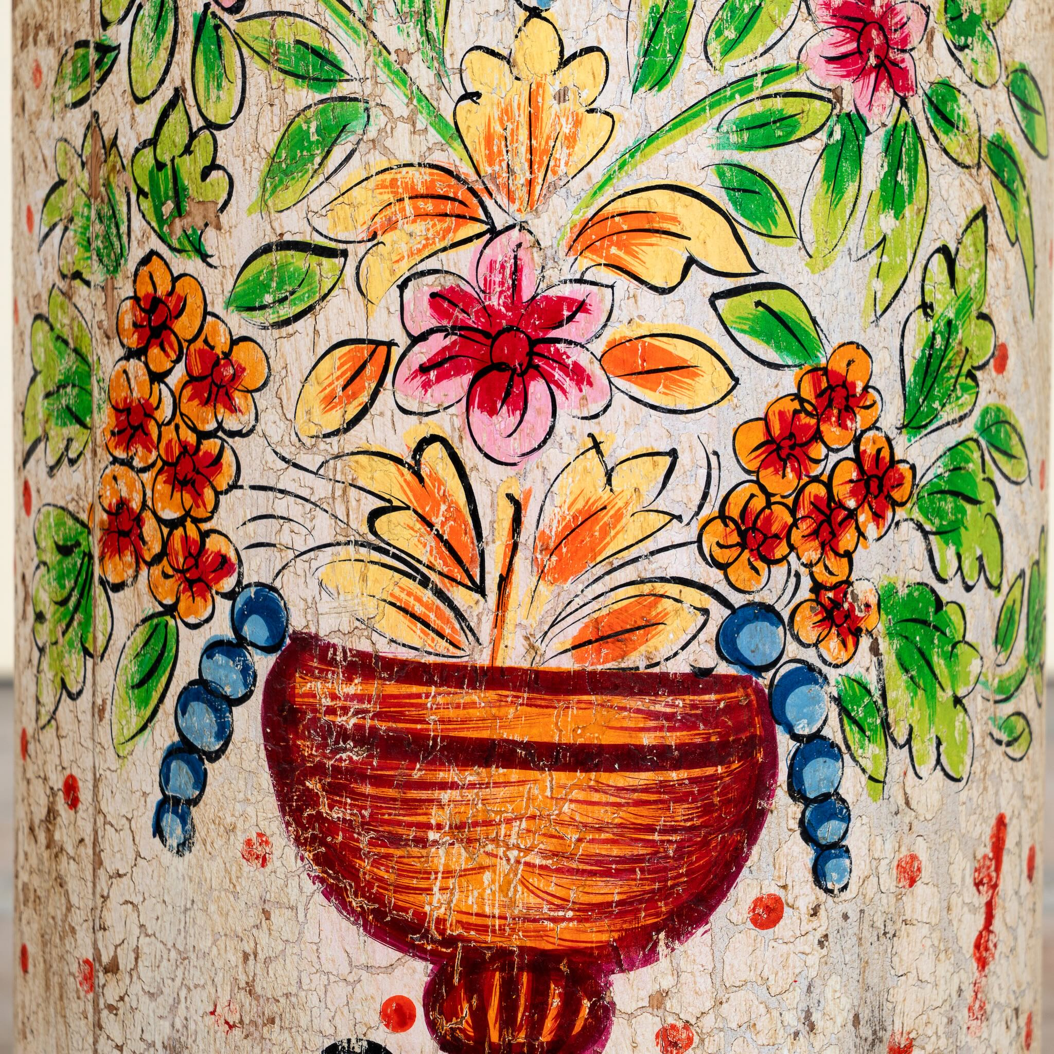 Close up image of a hand‑painted wooden side table with floral motifs in vibrant colours, perfect for bohemian interiors and artisanal furniture displays.