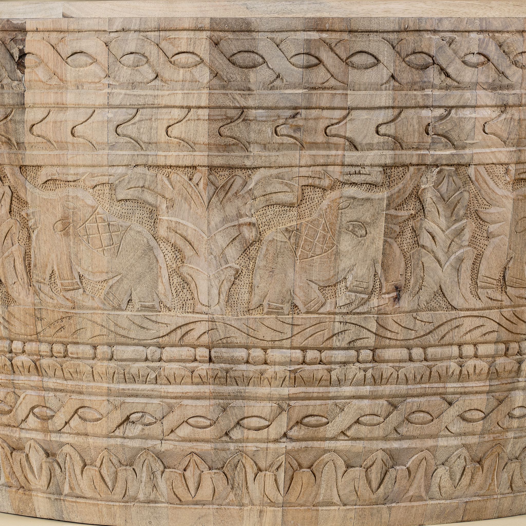 Close up image of a hand-carved mango wood coffee table with intricate botanical and geometric carvings.