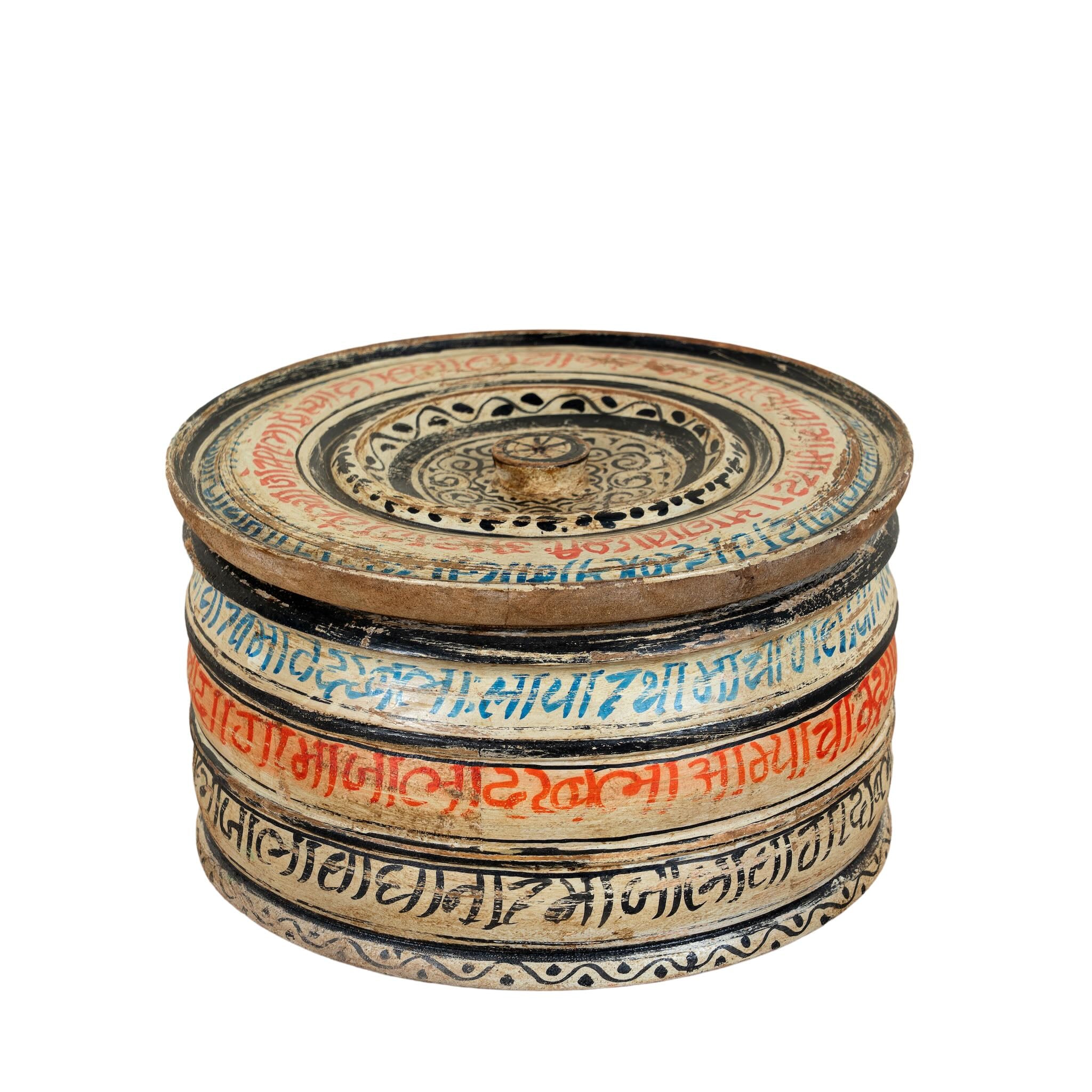 Hand-painted round wooden box with lid, featuring traditional Indian script and decorative motifs in red, blue, and black. A unique Indian decor item used for storage or display, available in four different designs.