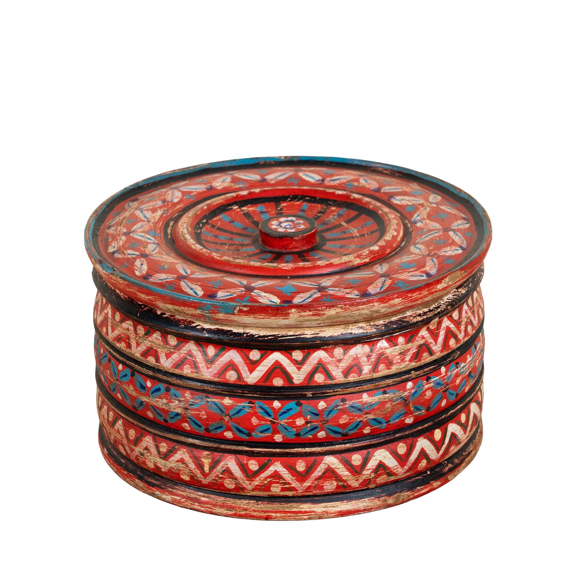 White background image of a hand-painted round wooden box with lid, featuring traditional Indian script and decorative motifs in red, blue, and black. A unique Indian decor item used for storage or display, available in four different designs.
