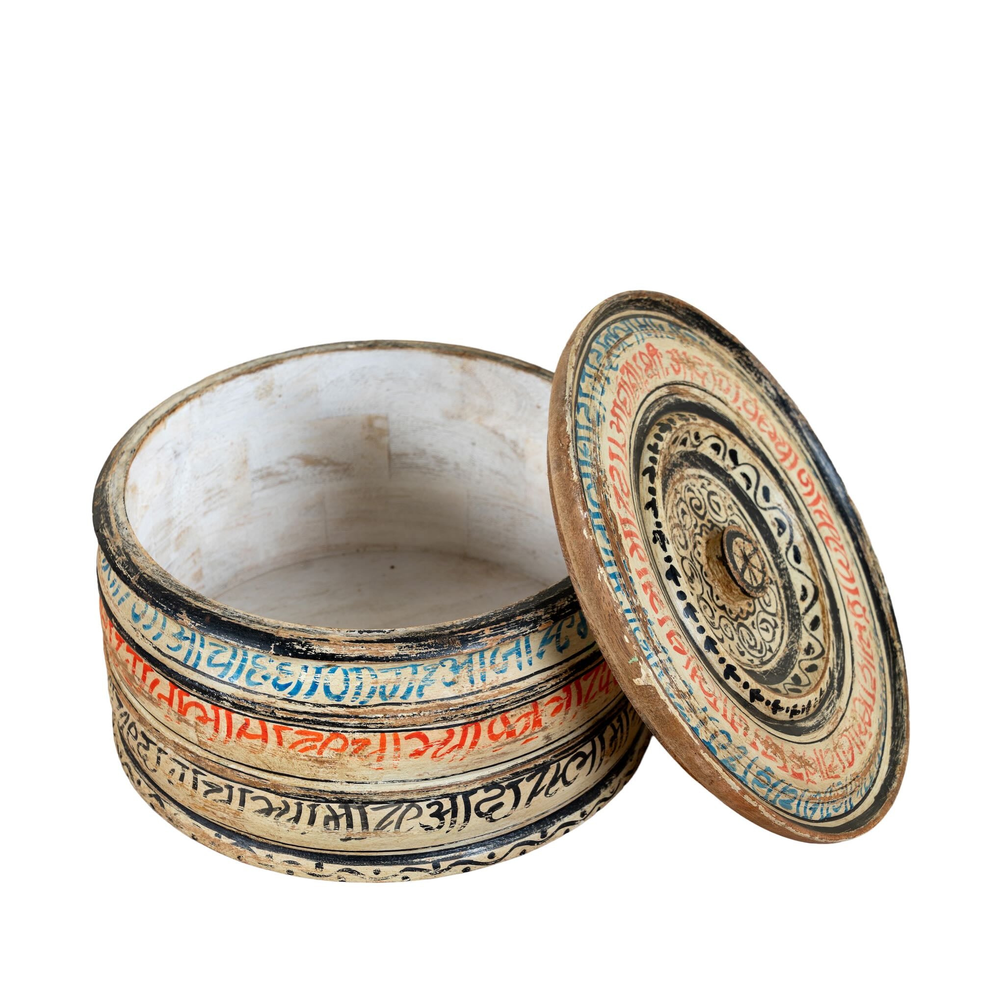 Hand-painted round wooden box with lid, featuring traditional Indian script and decorative motifs in red, blue, and black. A unique Indian decor item used for storage or display, available in four different designs.