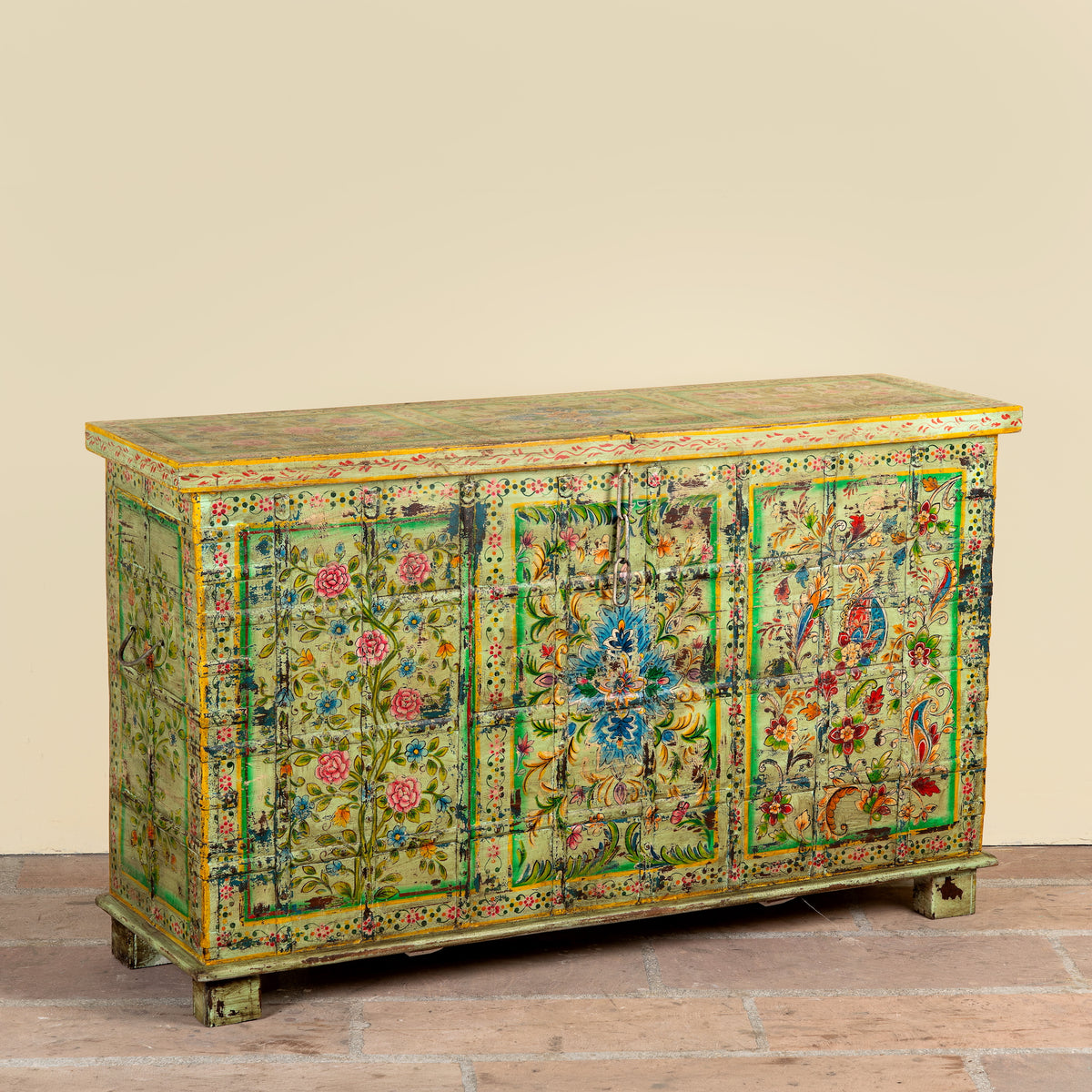 Side angle image of a Ruturaj hand painted reclaimed Indian teak wood chest with colourful floral motifs and iron fittings 150cm