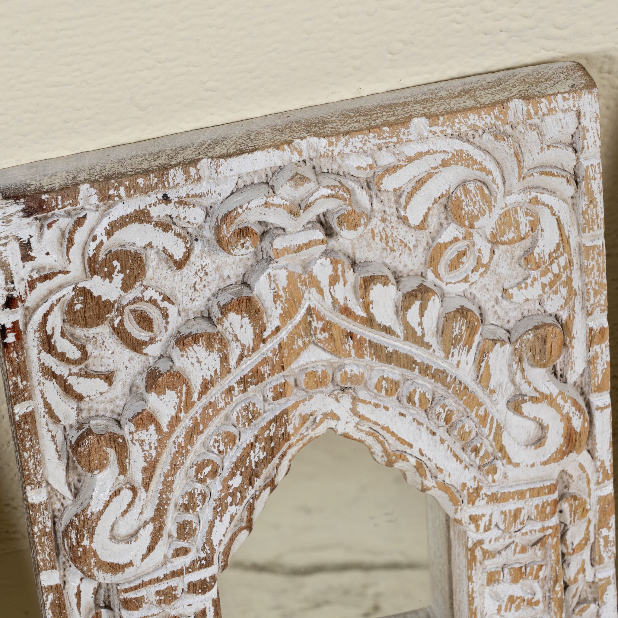 Close up image of a hand-carved wooden wall mirrors Sathvik with ornate jharokha arches and floral detailing, available in various vintage finishes. A unique Indian decoration and vintage home accessory perfect for vintage home decor settings.
