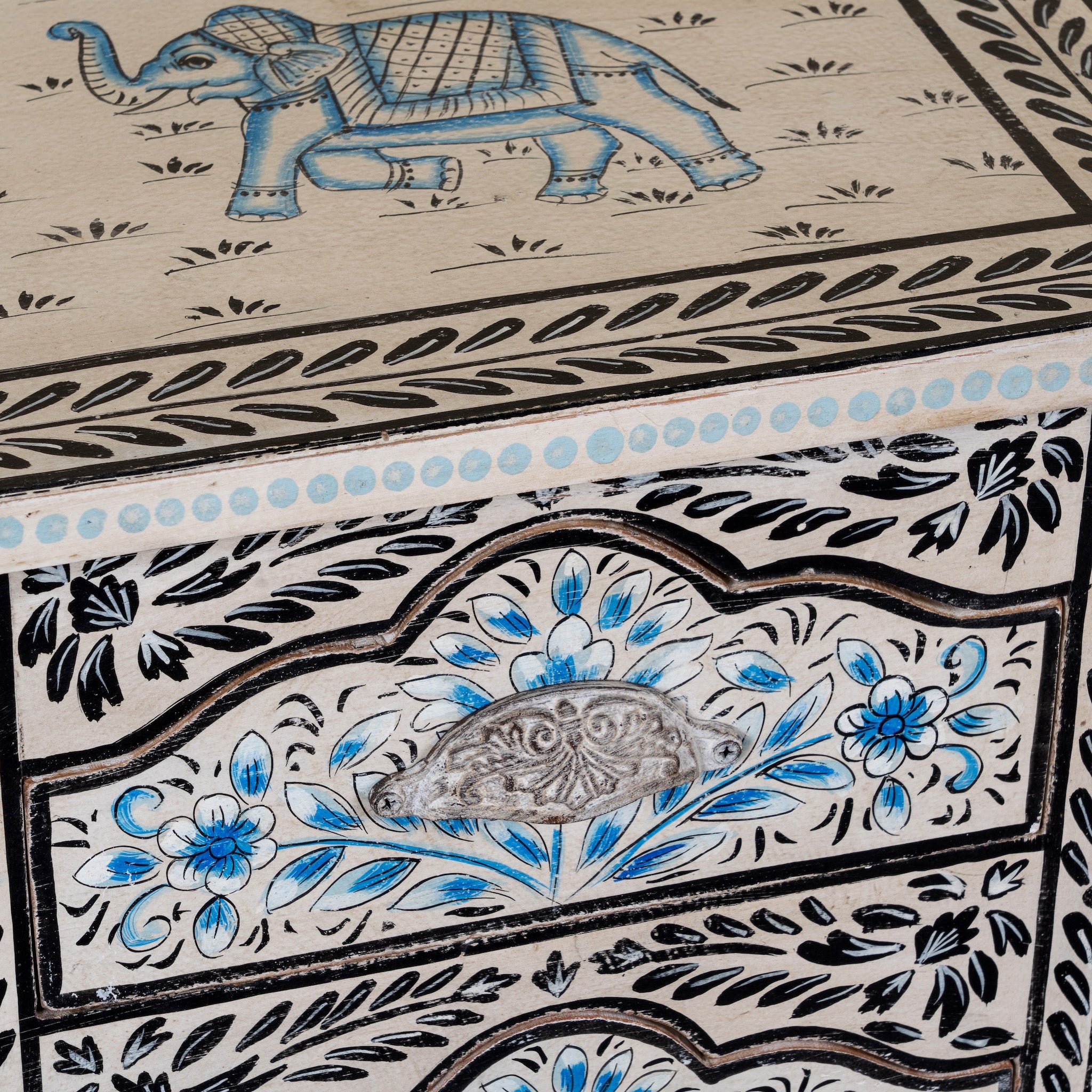 Close up image of a pair of hand-painted nightstands made from reclaimed wood, featuring floral motifs in soft turquoise and black with intricate carved detailing and two drawers for storage.