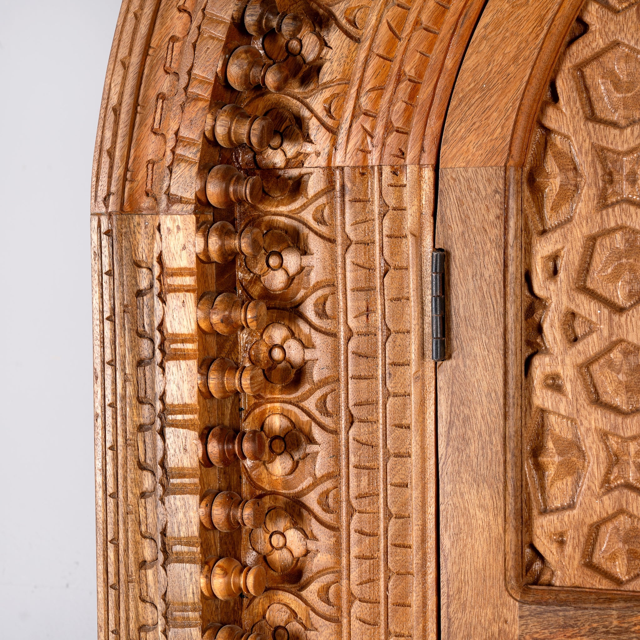 Close up image of a Shivaaya hand carved mango wood cabinet with geometric double doors and arched top 210cm