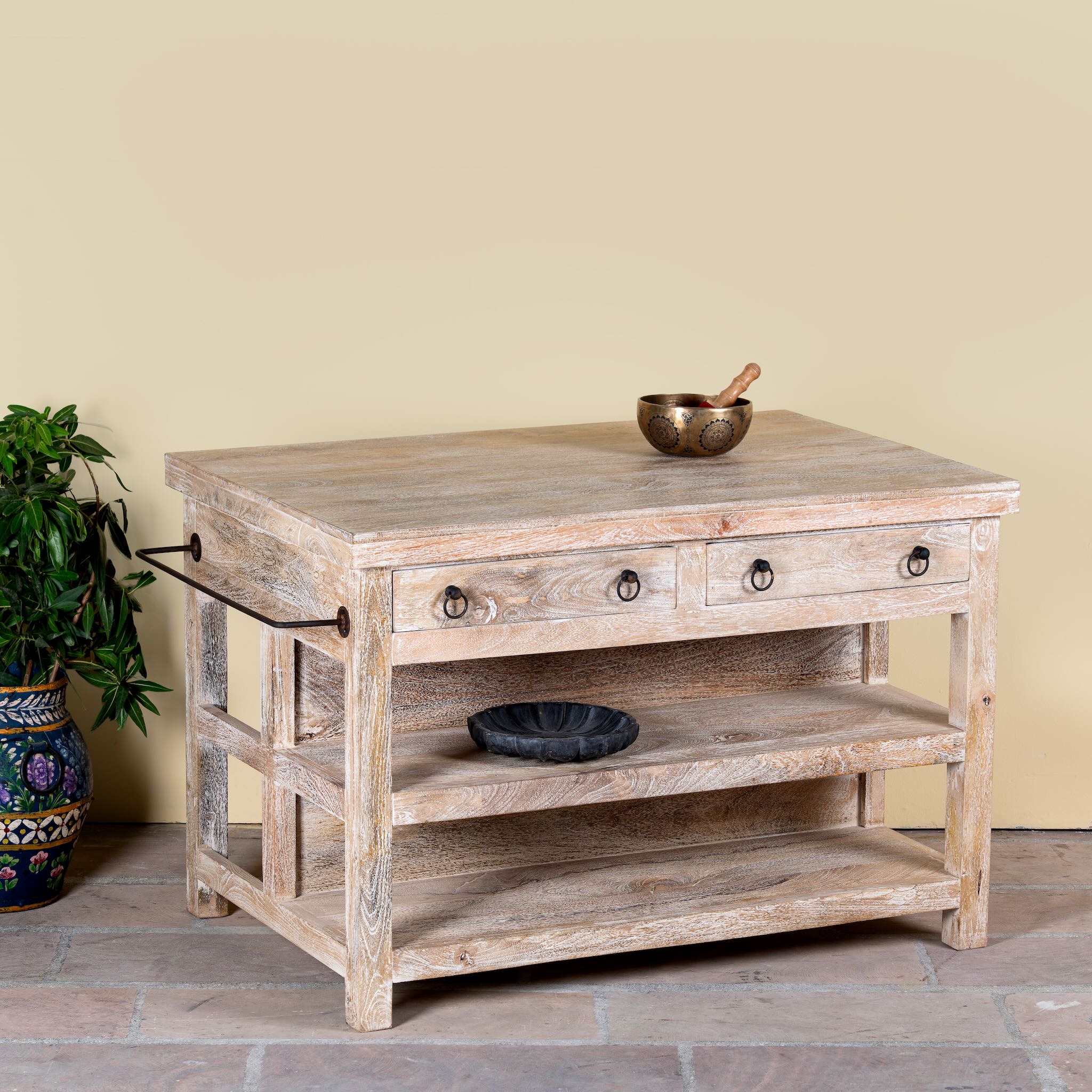 Side angle image of a white washed mango wood console table with 4 drawers and shelves. Solid wood counter table with rustic vintage look and storage.