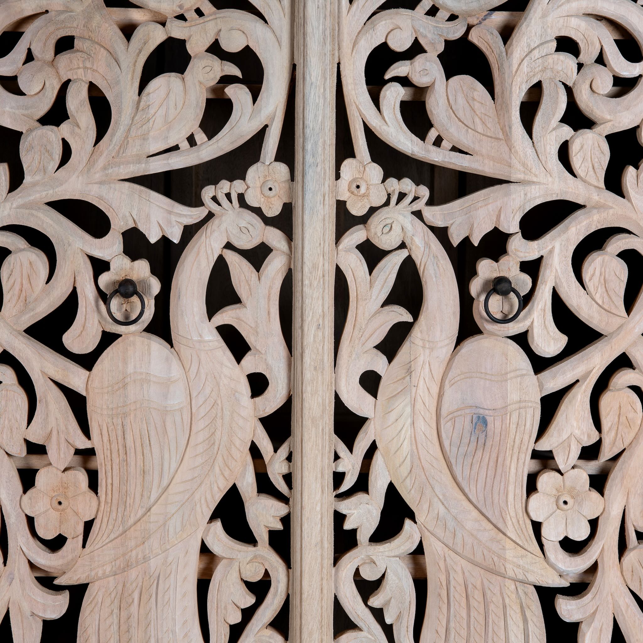 Close up image of a hand-carved mango wood wardrobe with arched top and intricate peacock floral design – artisanal Indian bedroom furniture.