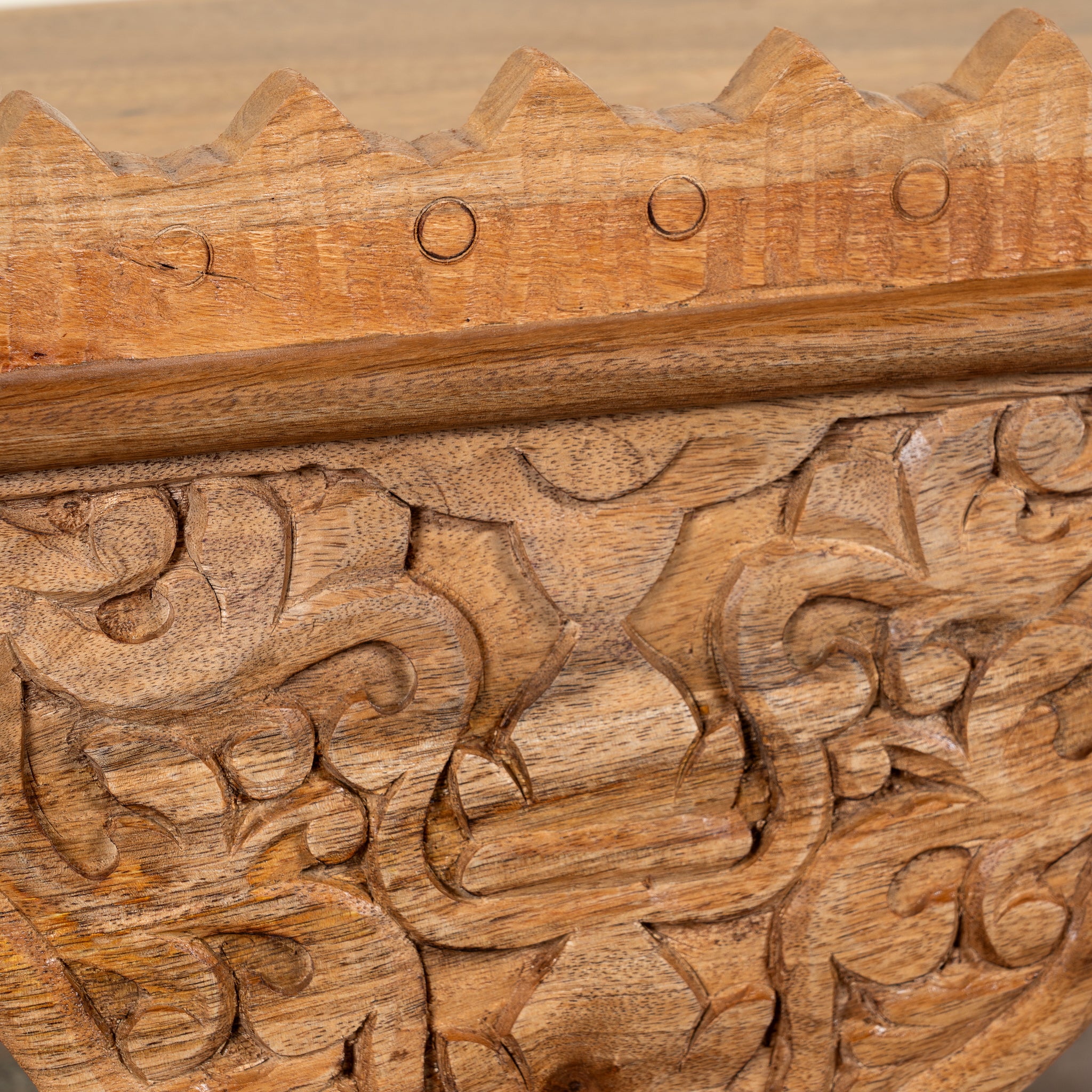 close up image of a Tanira hand carved mango wood wall shelf with floral carvings and decorative hanging leaf details 60cm