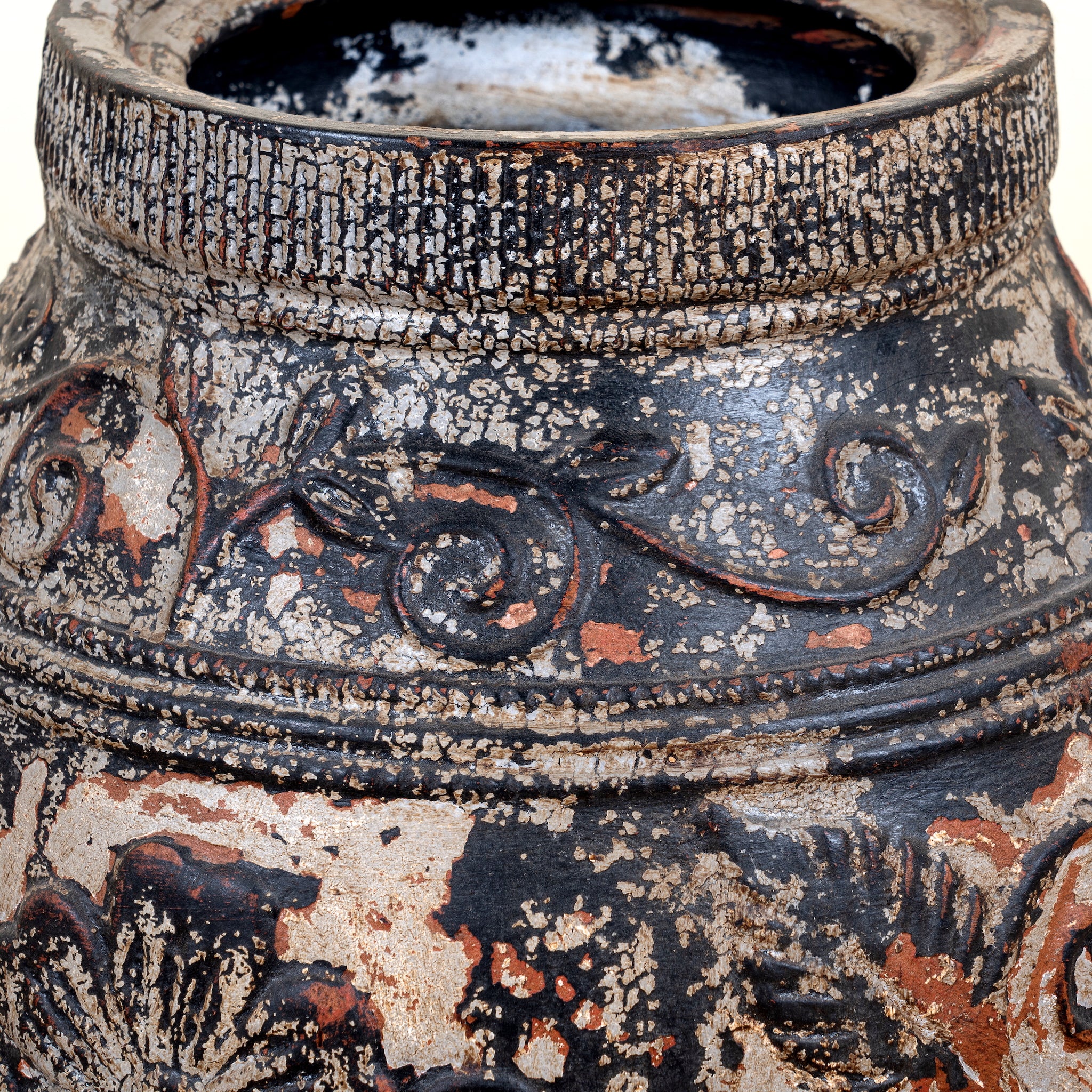 Close up image of a hand-painted clay vase with vintage distressed charcoal and terracotta finish, raised floral relief decoration, 33x35cm.