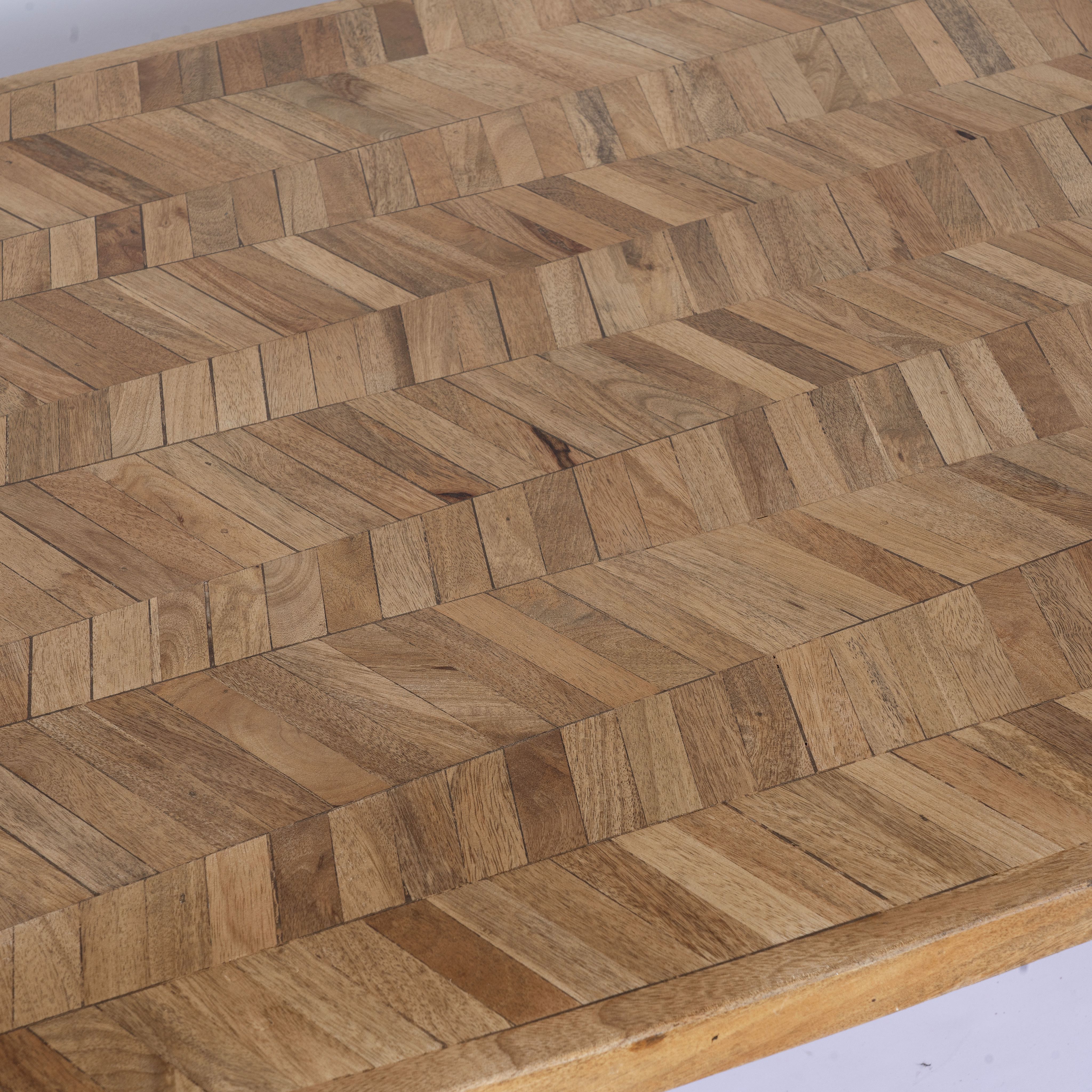 Close up image of a Uddanda mango wood dining table featuring an intricately patterned natural wood tabletop with a brass-plated iron base and contemporary industrial design, 181cm.