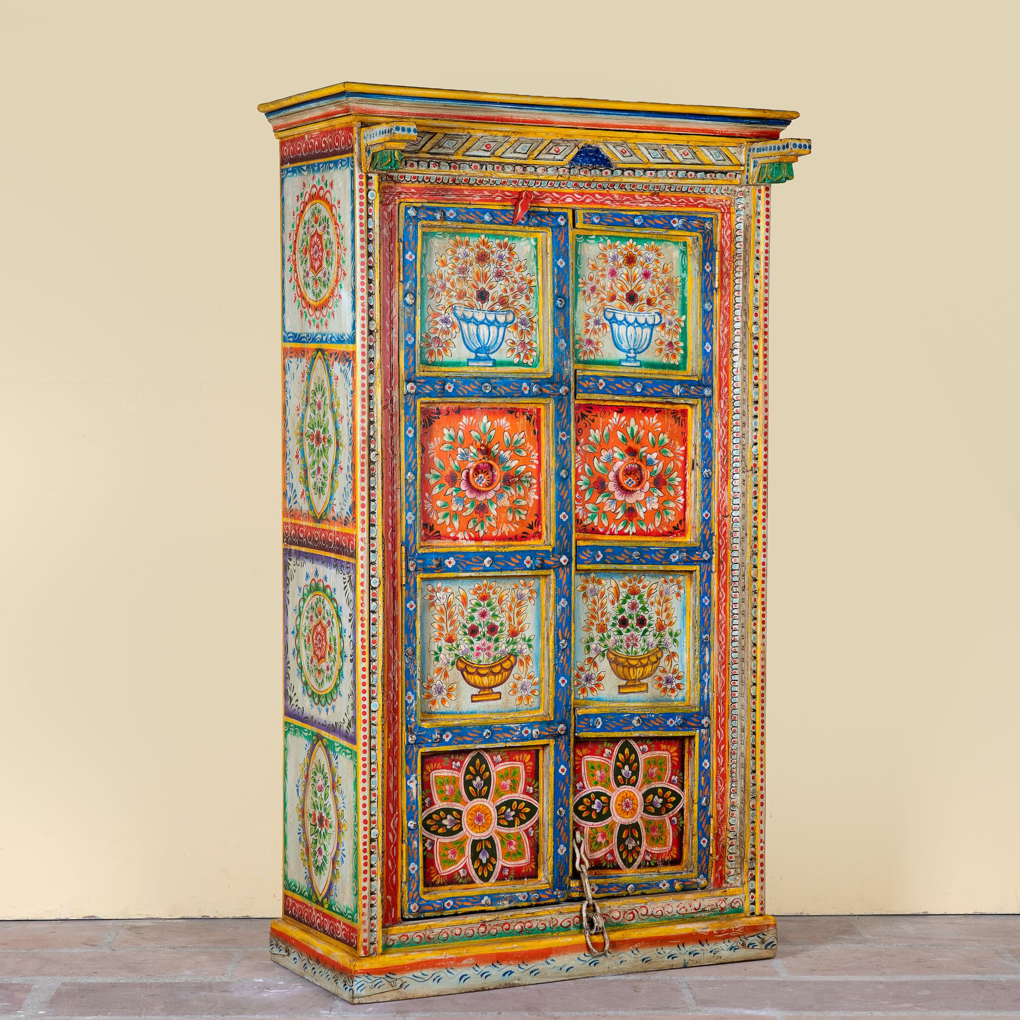 Side angle image of a hand-painted teak wood cabinet with floral motifs; teak wood furniture for bohemian interiors, 105 × 55 × 177 cm.