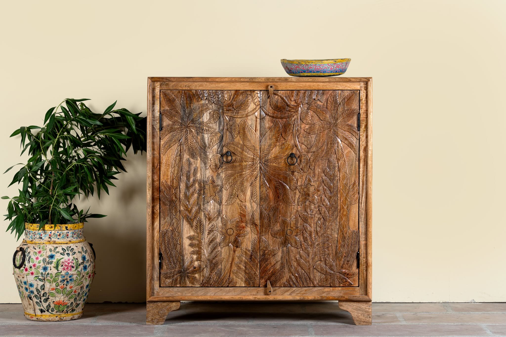 Hand-carved mango wood cupboard Vansh with double doors featuring intricate floral and botanical motifs. A Mediterranean-inspired piece of Indian furniture offering functional storage and timeless artisan detail.