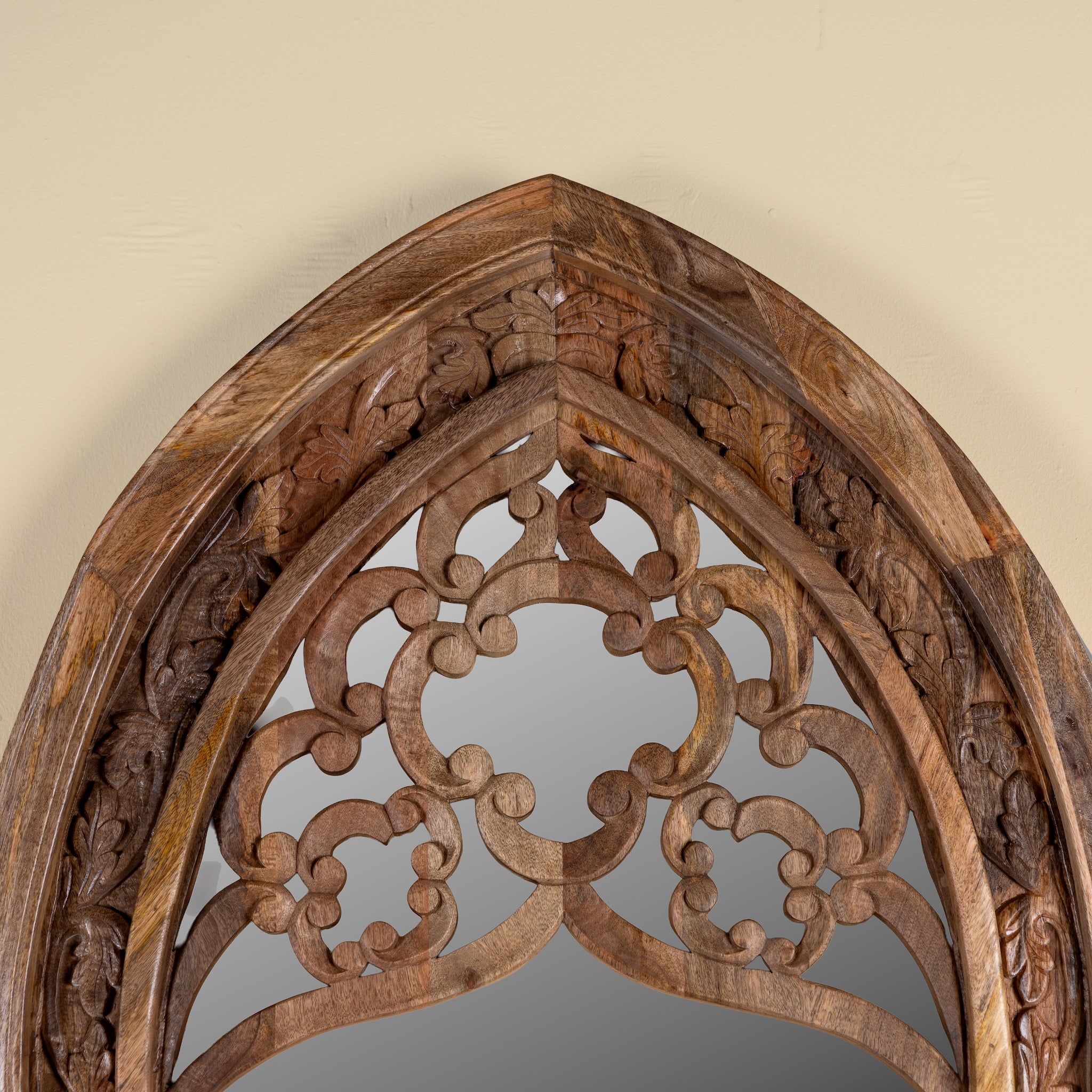 Close up image of a Veda hand carved mango wood arch mirror with decorative openwork frame and natural mango finish, 85x15x197cm