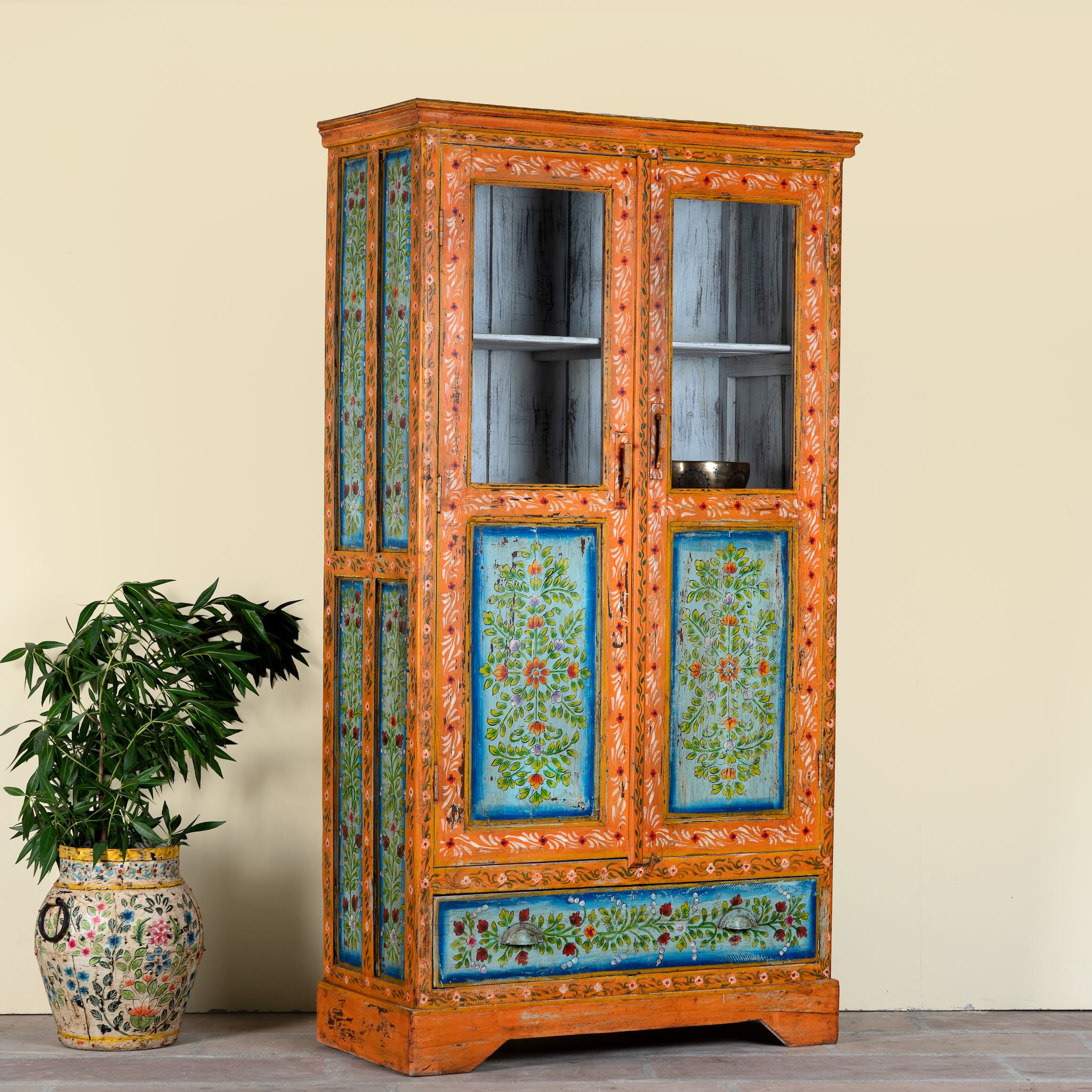 Side angle image of a vintage hand painted reclaimed wood showcase with 2 doors and one drawer.